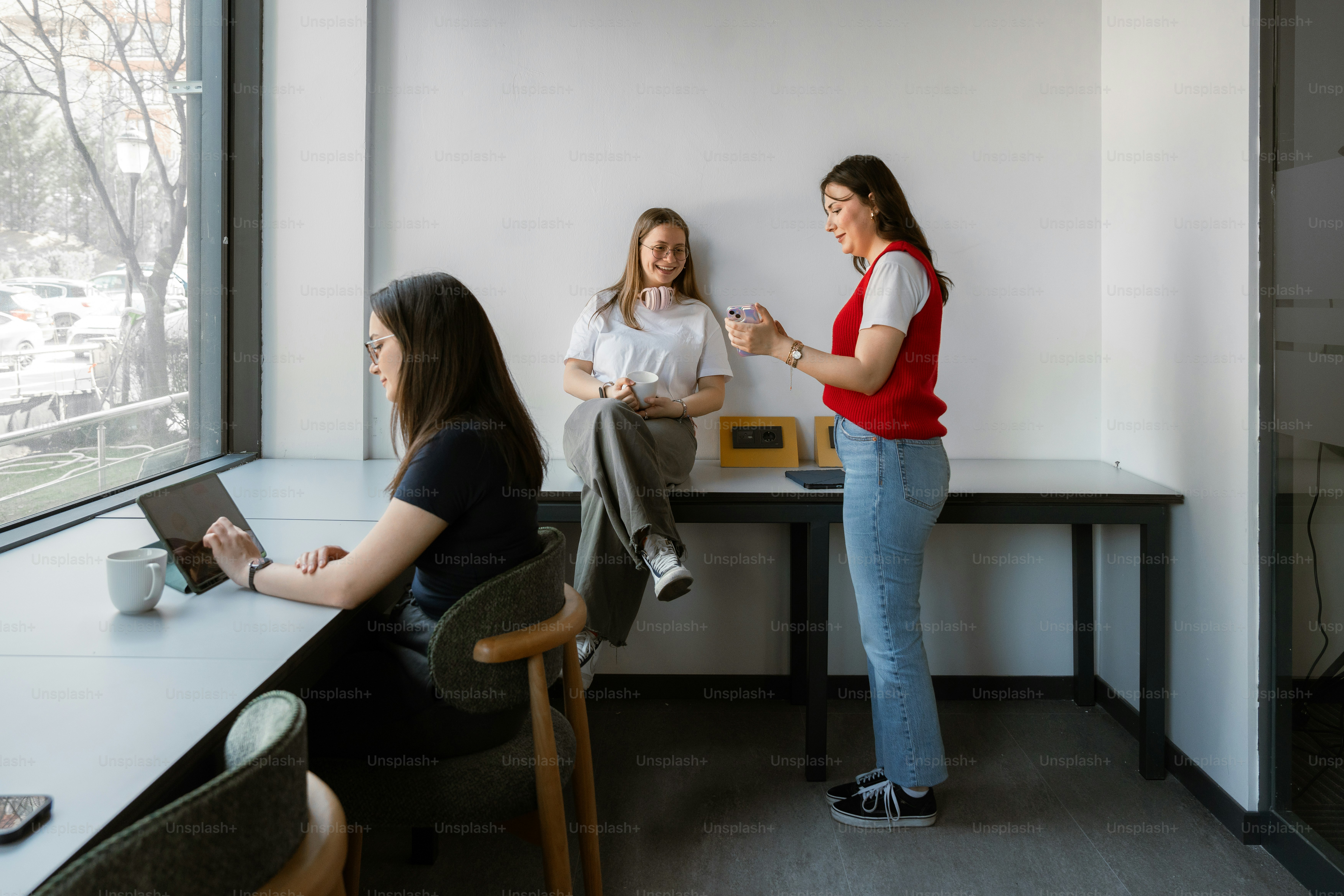 Three women are working and chatting in an office.