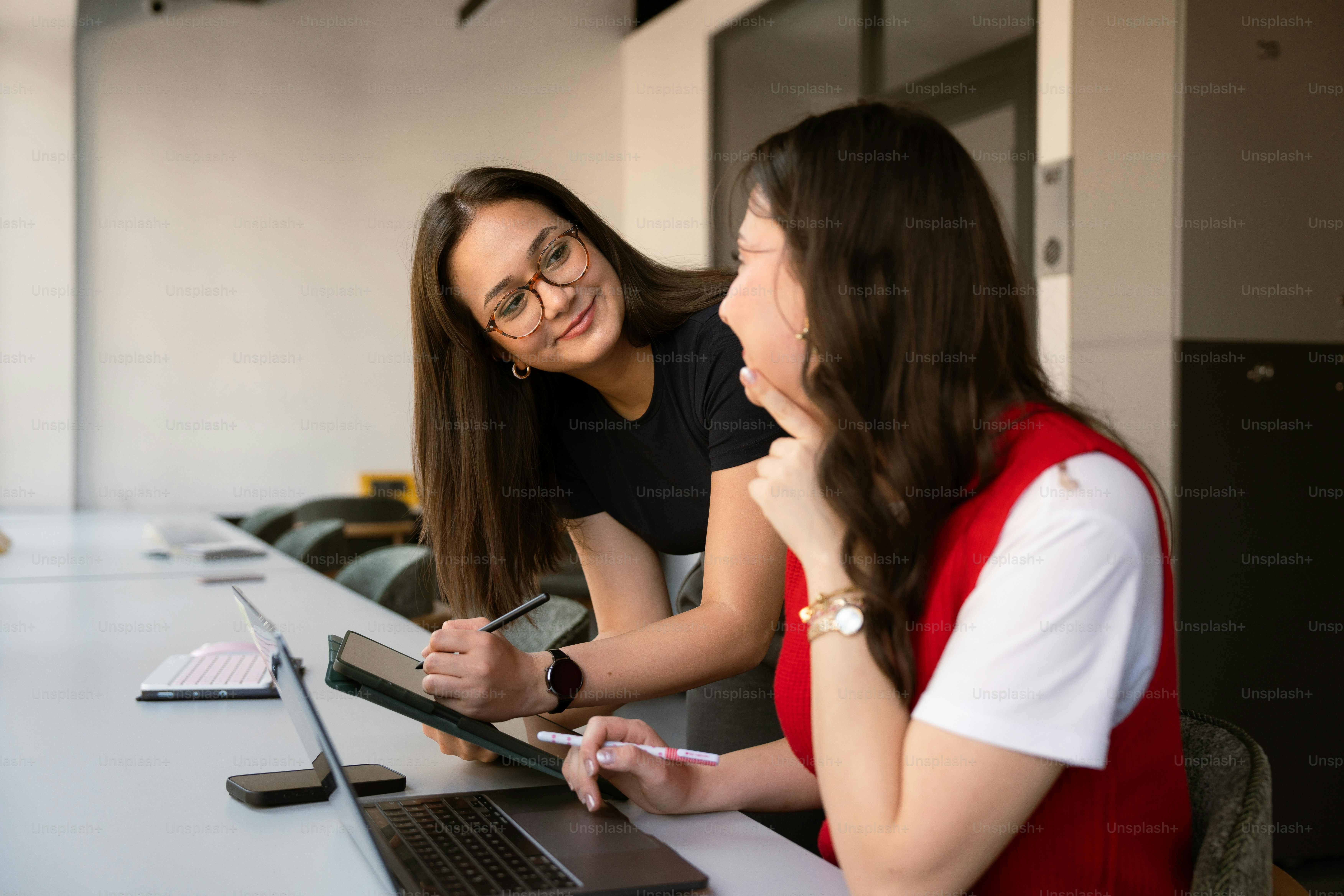 オフィスのテーブルで協力する2人の女性。