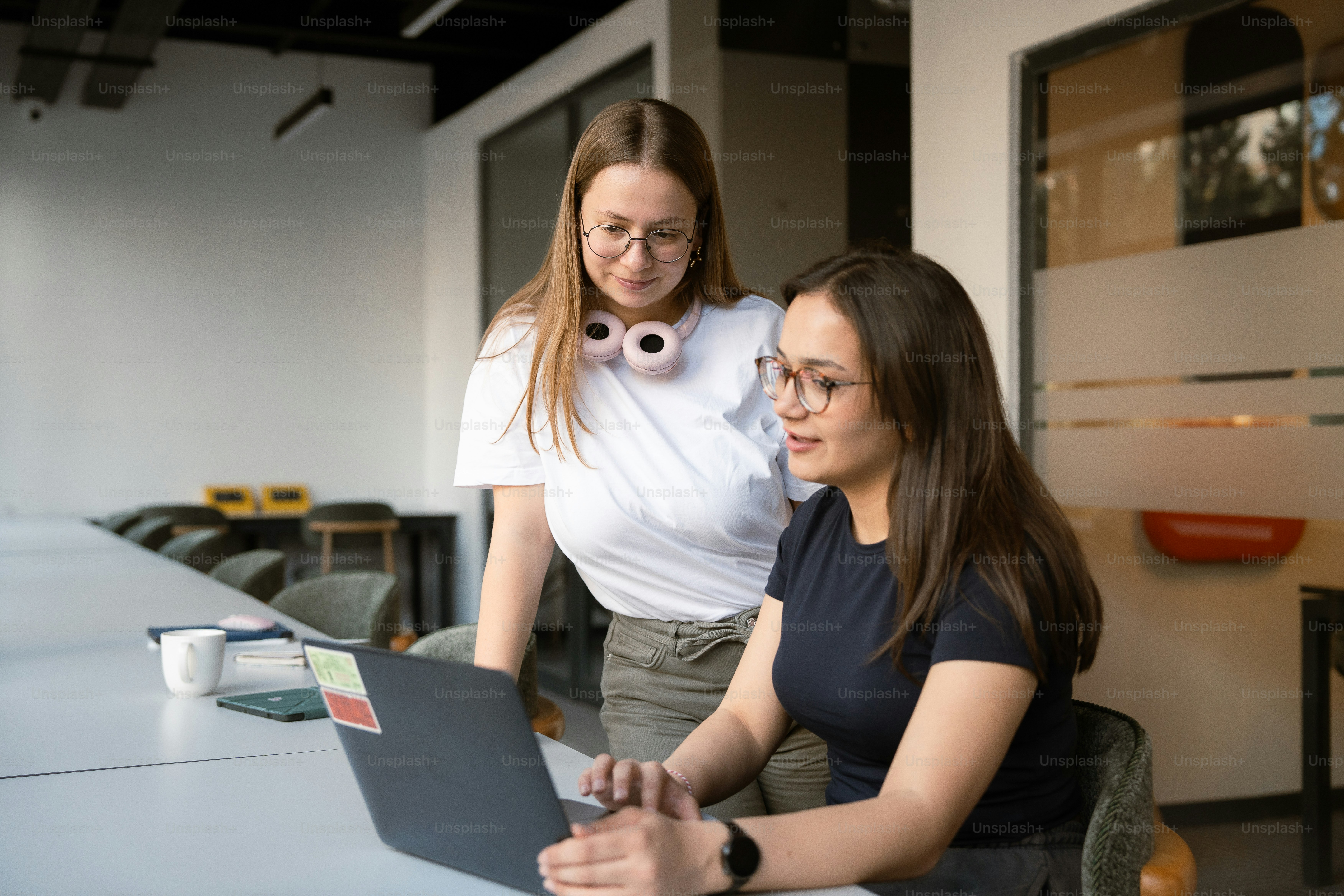 Two women collaborate around a laptop.