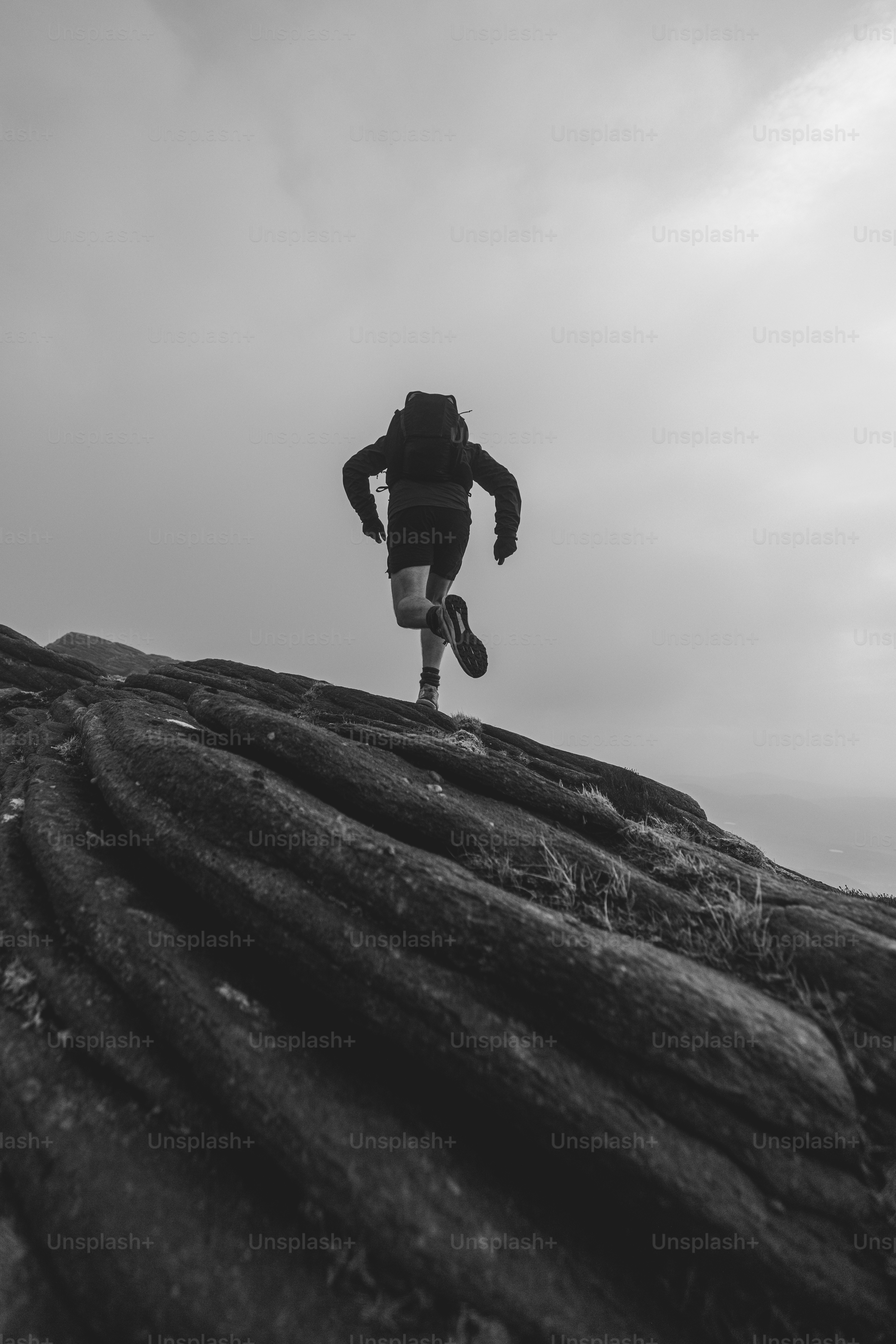 El excursionista corre por la roca con una mochila pesada.