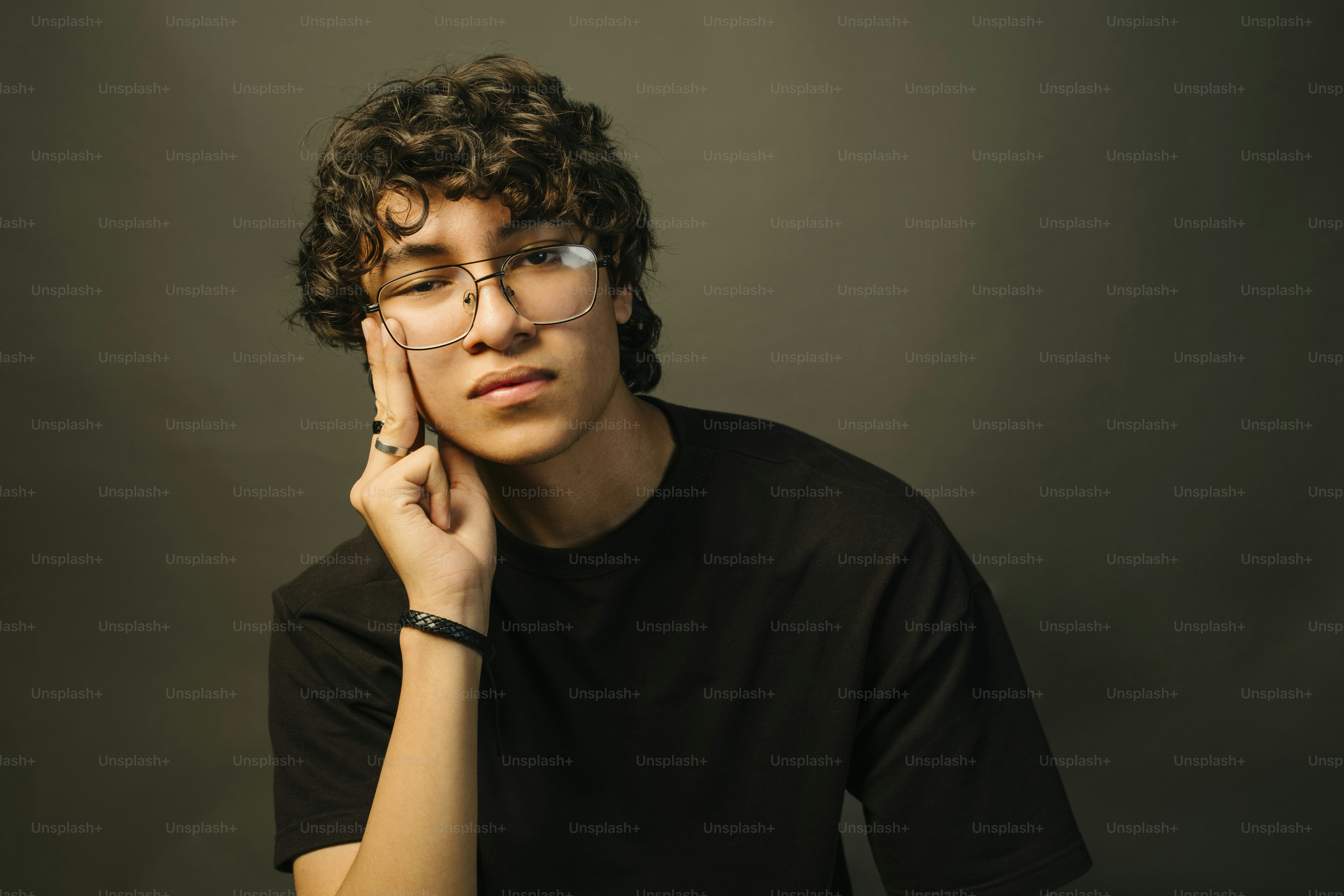 A young man poses pensively in a studio