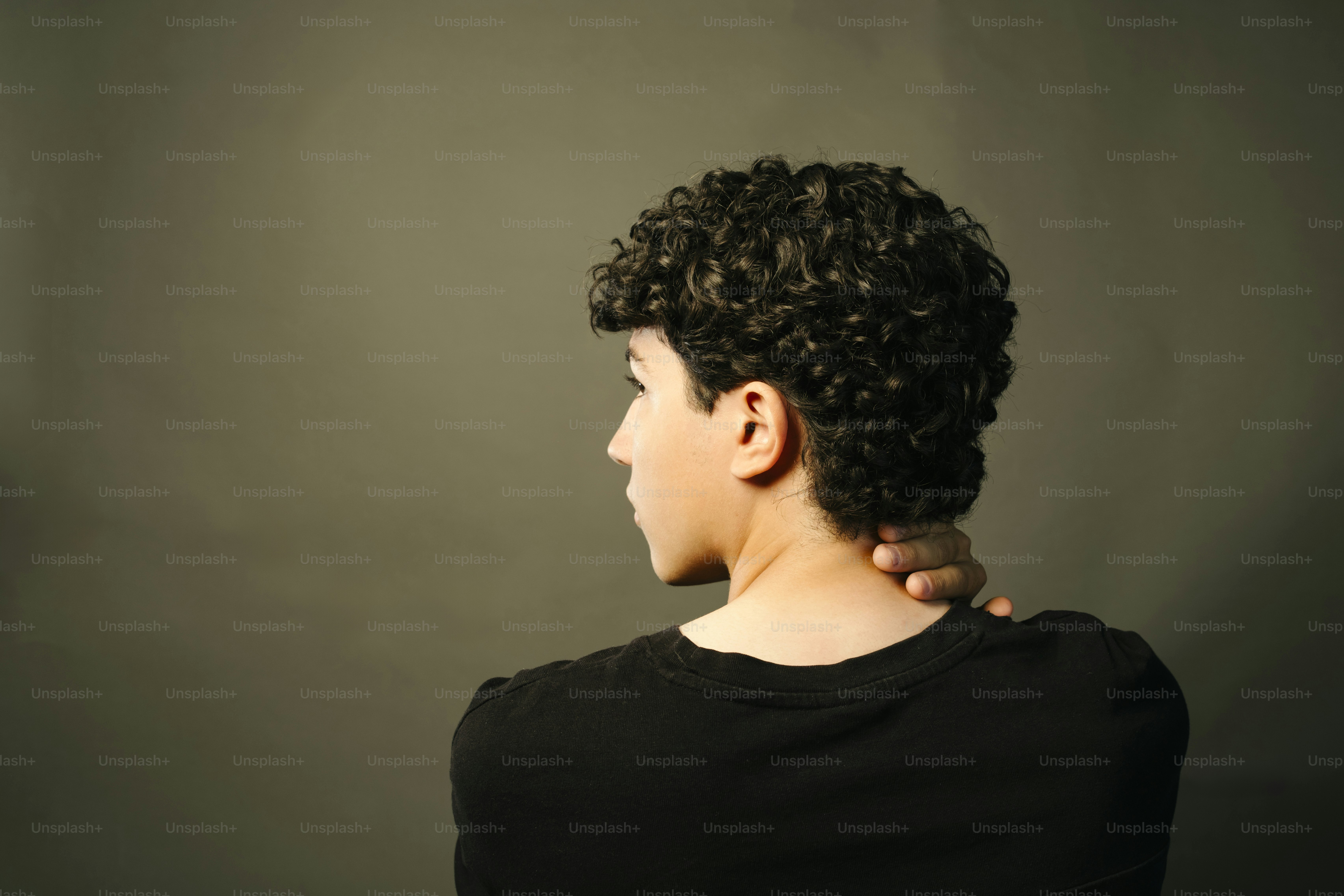 A young person with curly hair looks away