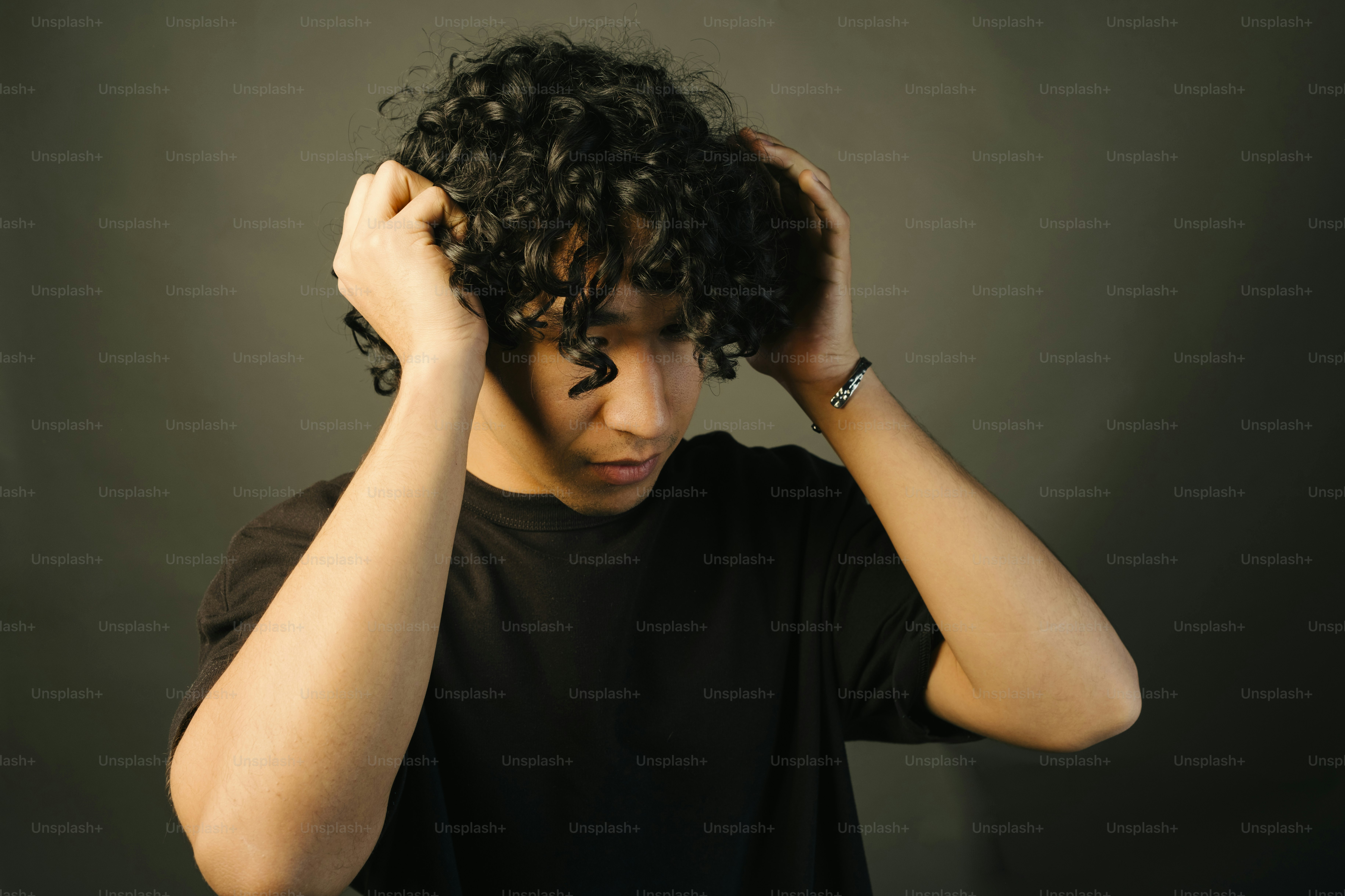 A young man is fixing his curly hair.