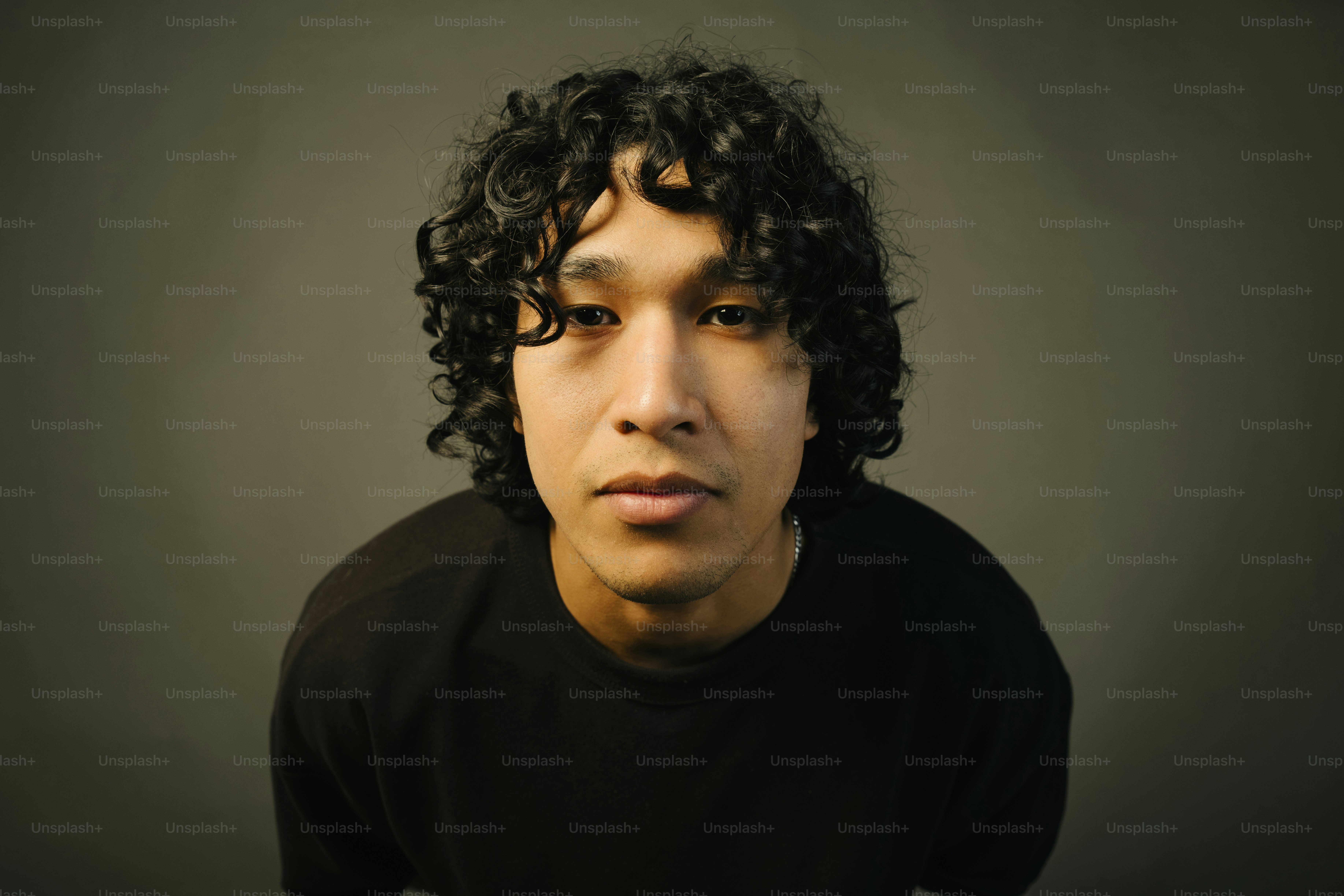 A young man with curly hair is posing