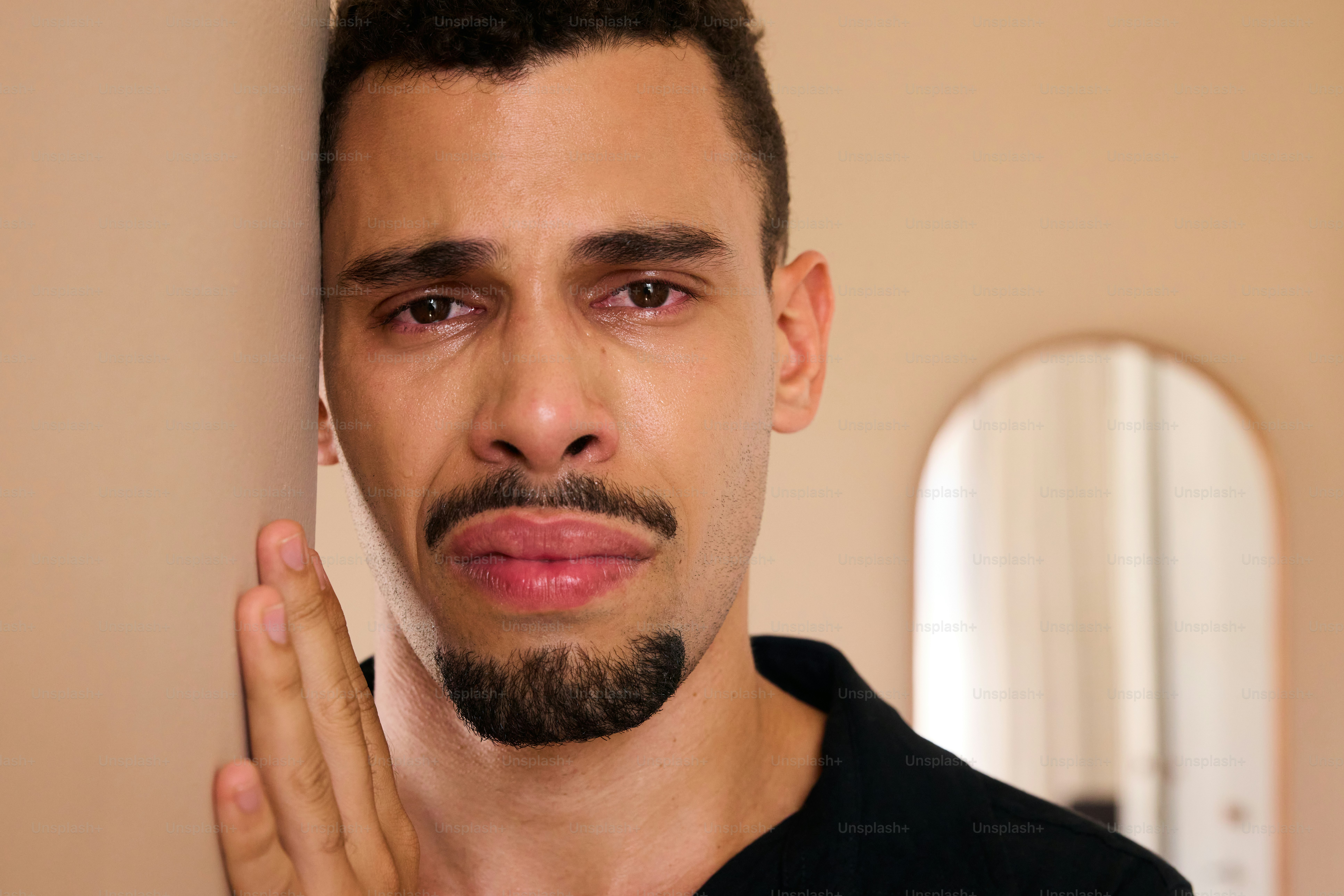 A man is crying and leaning against the wall.