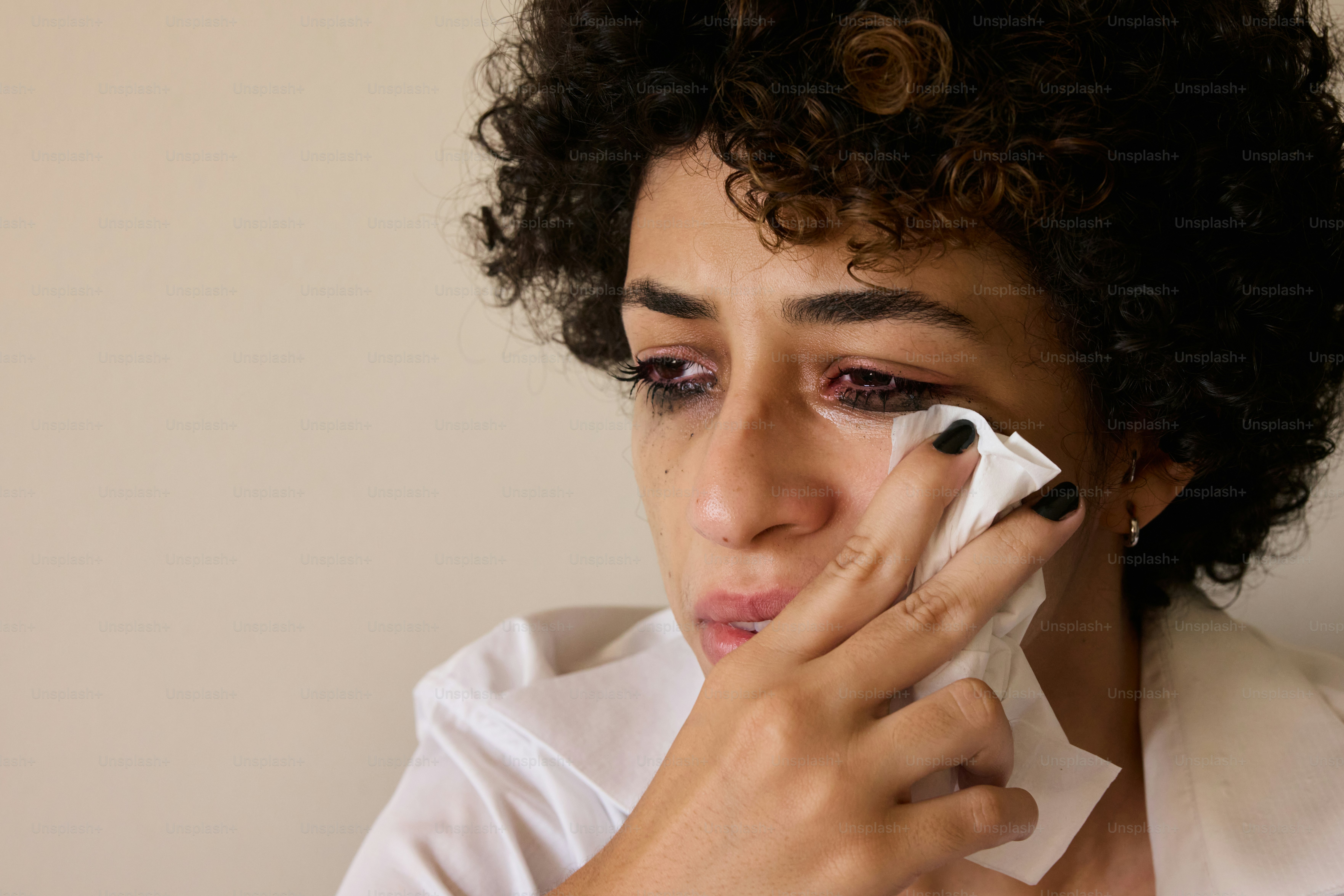 Una mujer llora, secándose las lágrimas de los ojos.