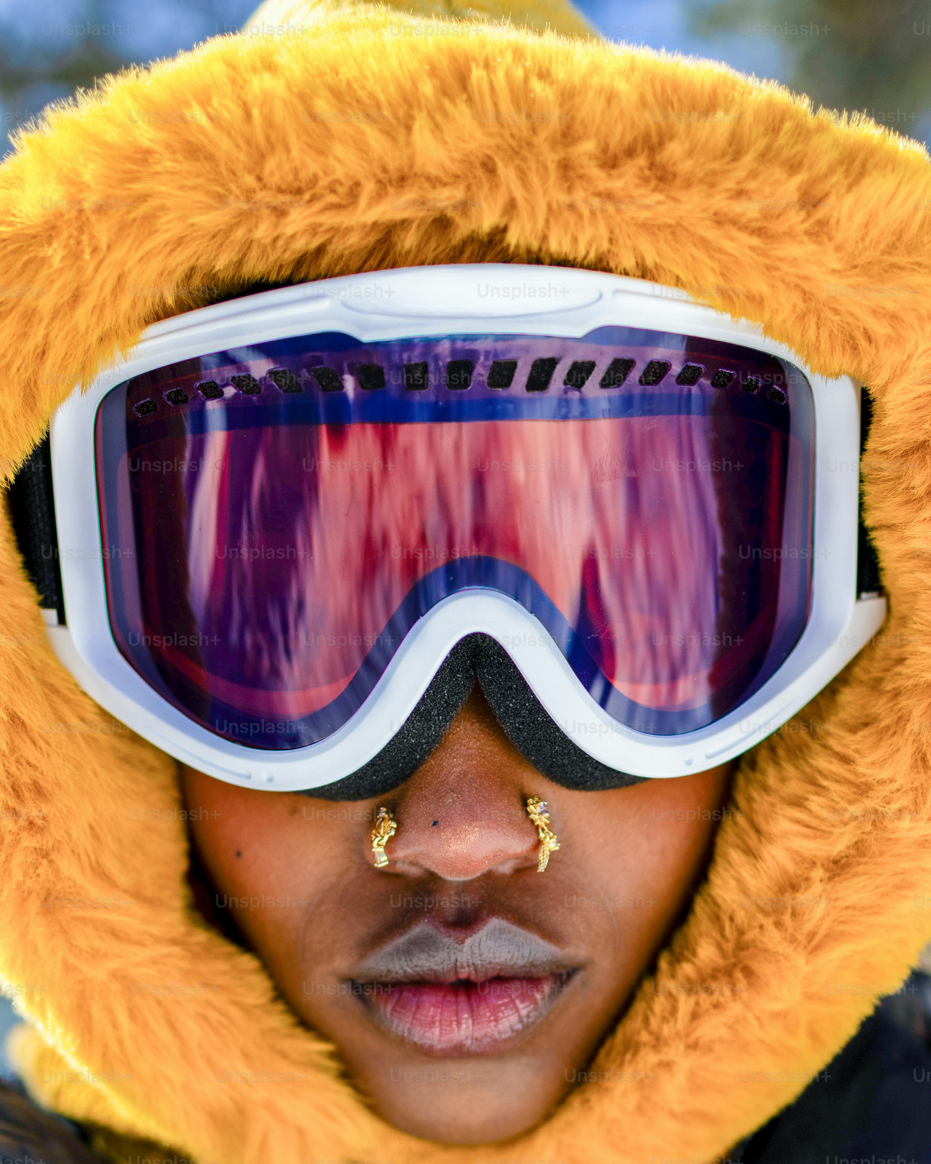 Una persona che indossa occhiali da sci e un cappuccio giallo.