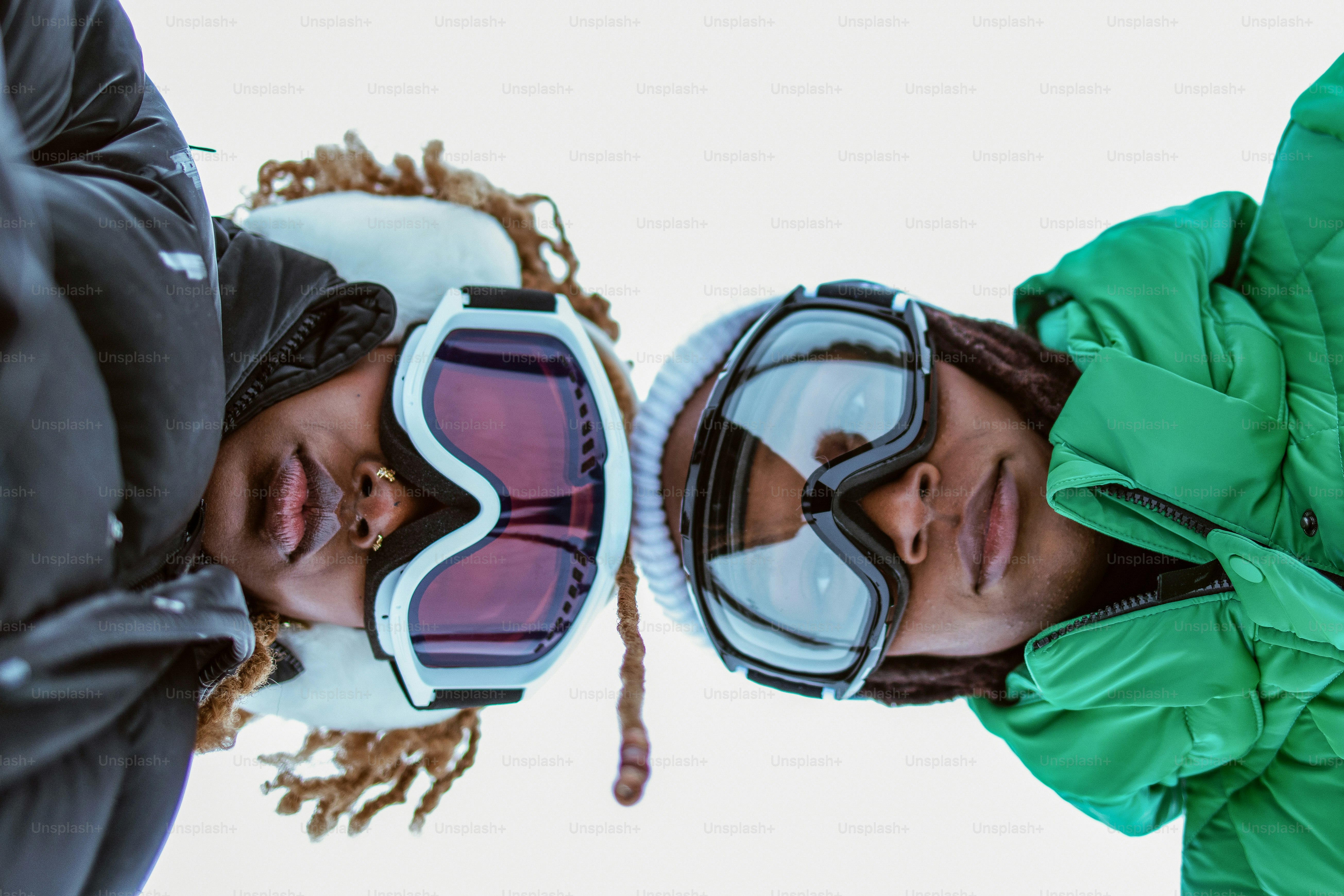 Two people wear ski goggles and look at camera.