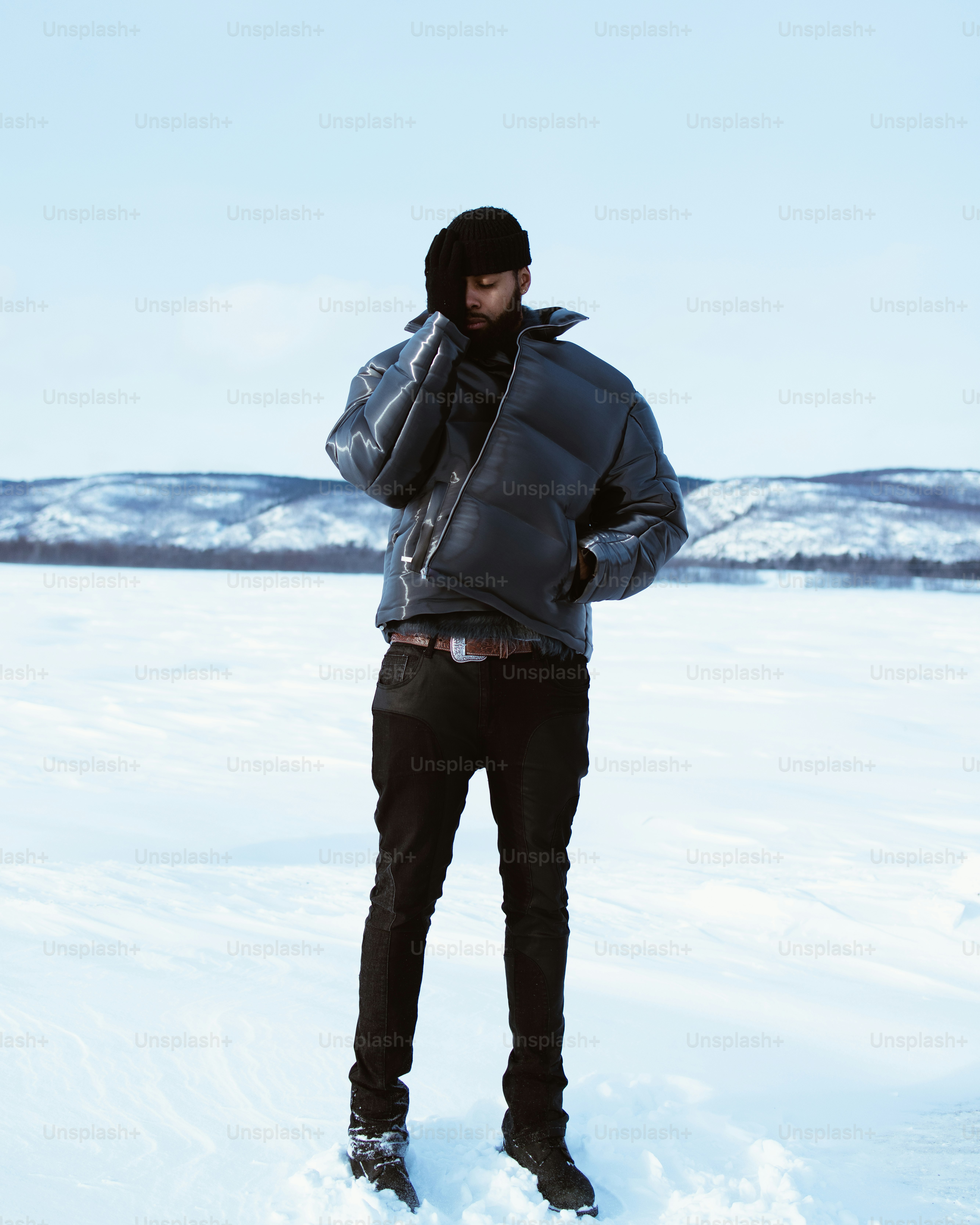 Man stands in the snow, bundled in a jacket.