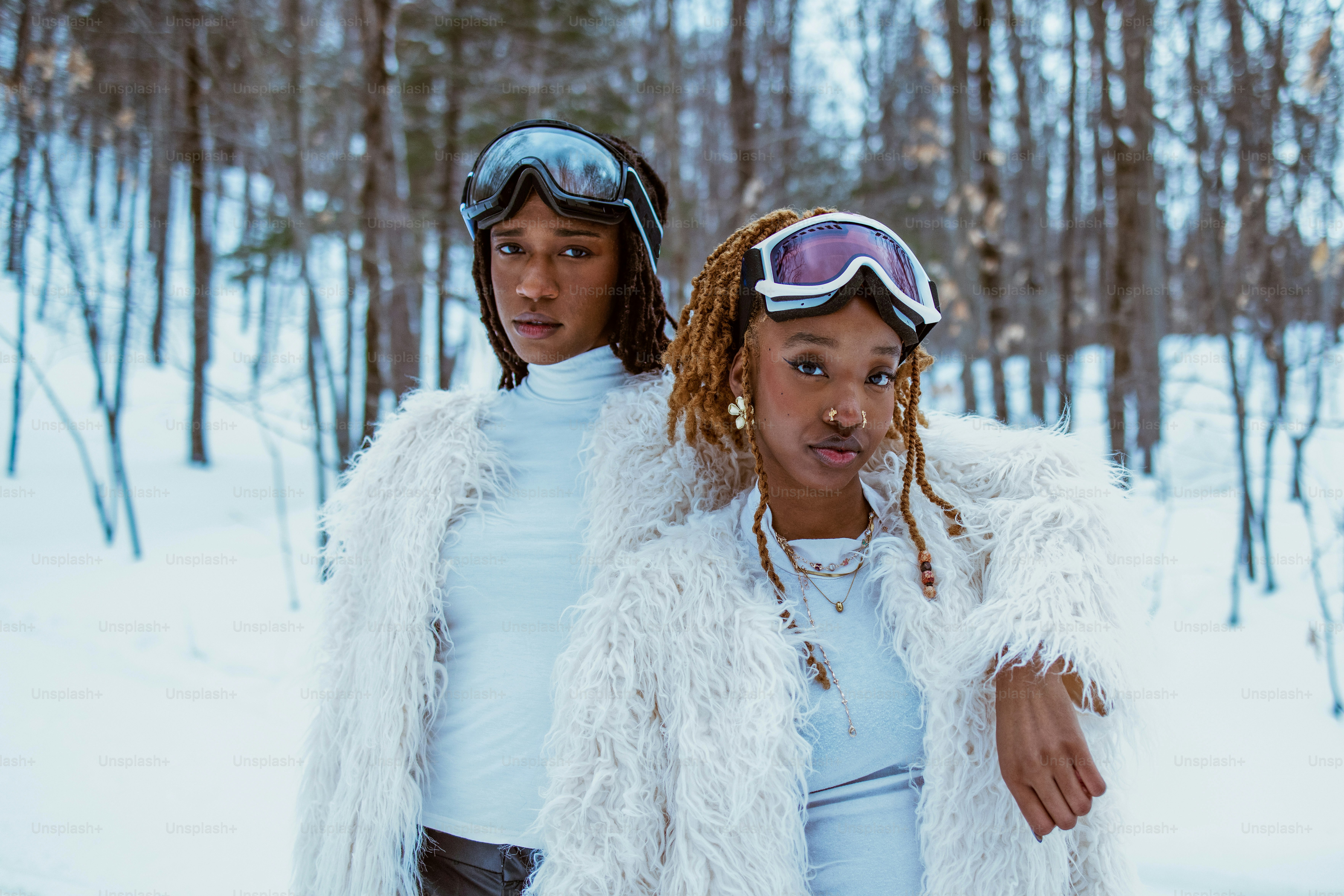 Two women pose in the snow with goggles on.