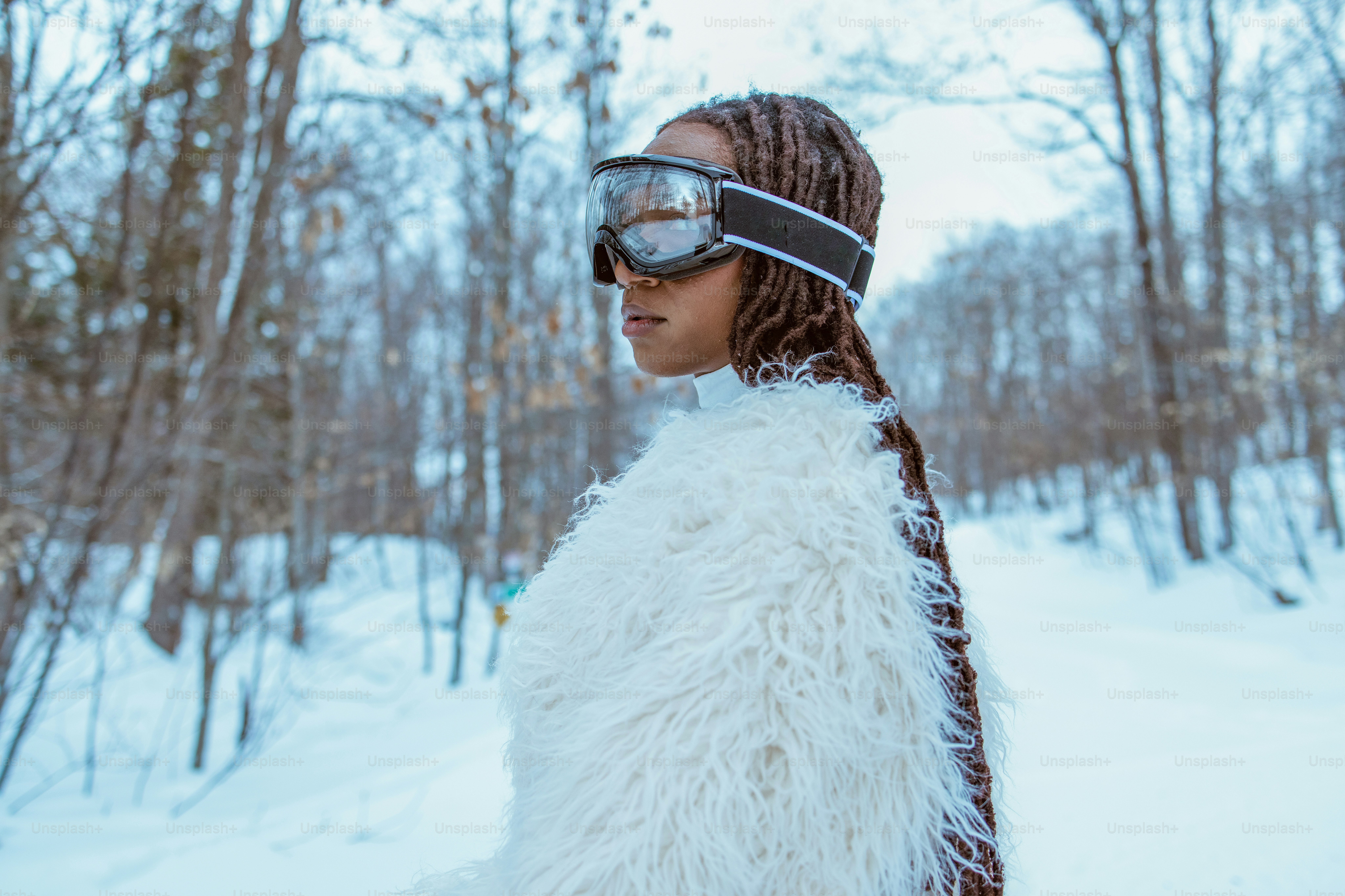 Person wearing goggles and fur coat in the snow.