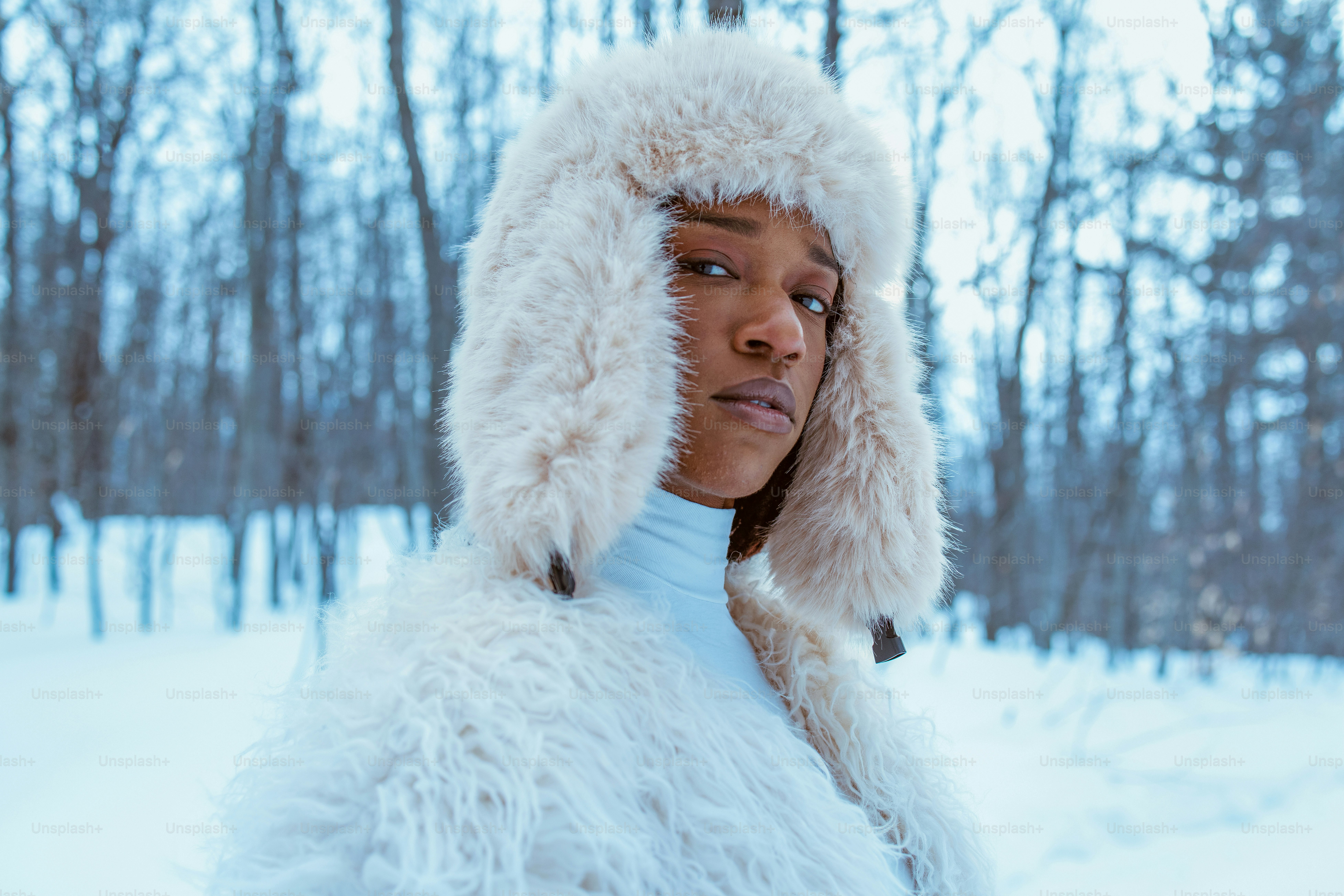 Person in furry winter attire poses in snow.