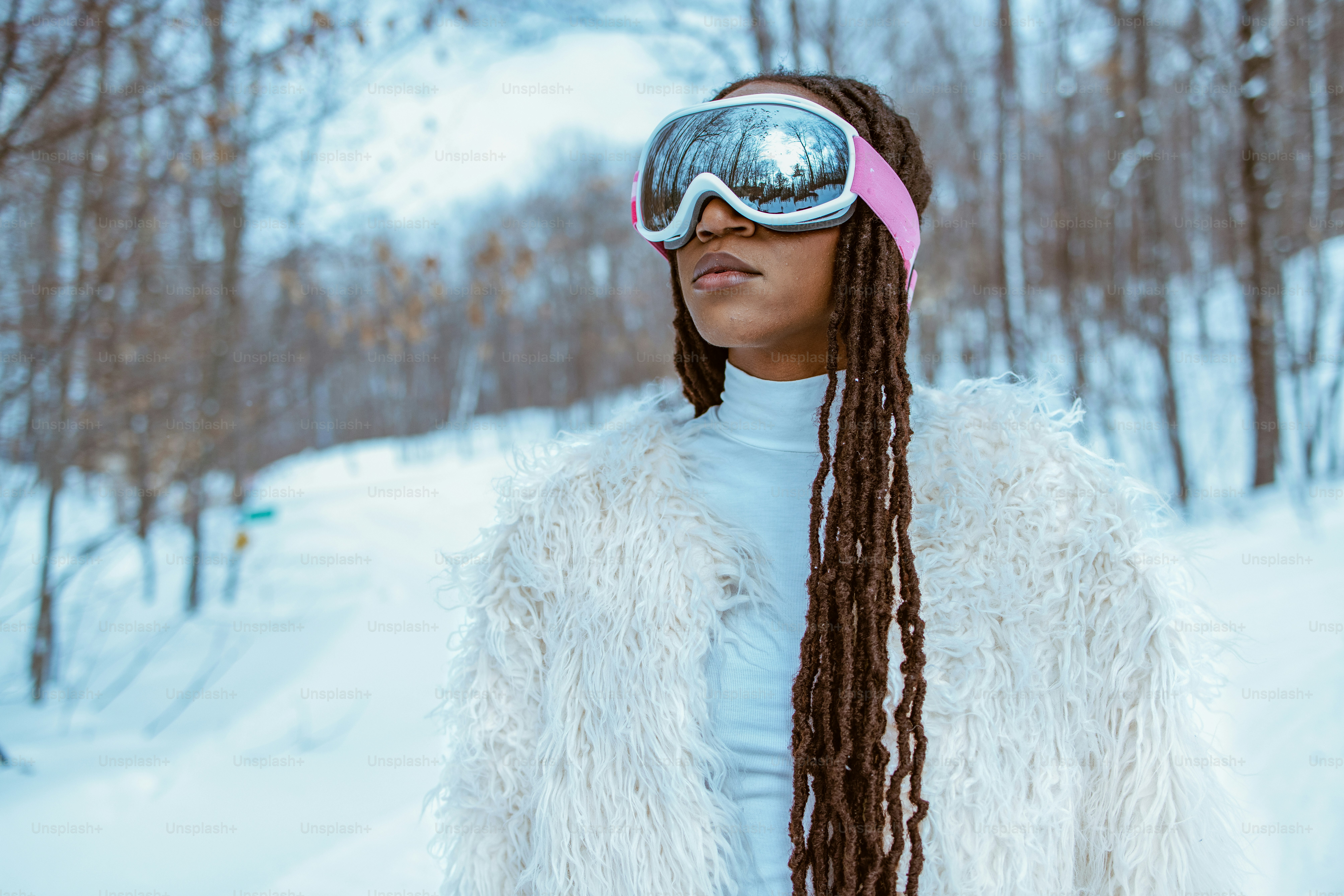 Woman in goggles and a furry coat in the snow.