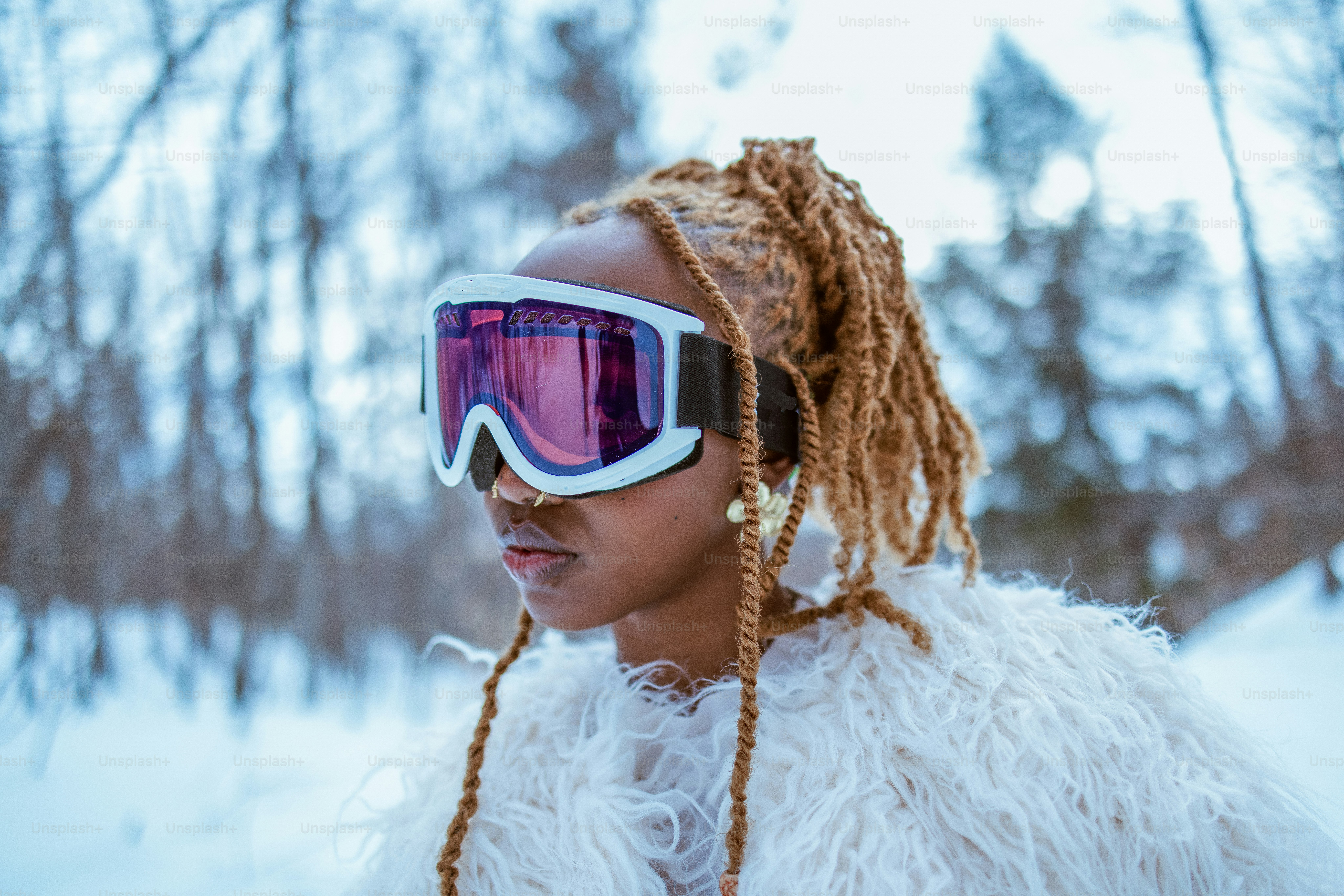 Woman in snow gear poses with goggles.