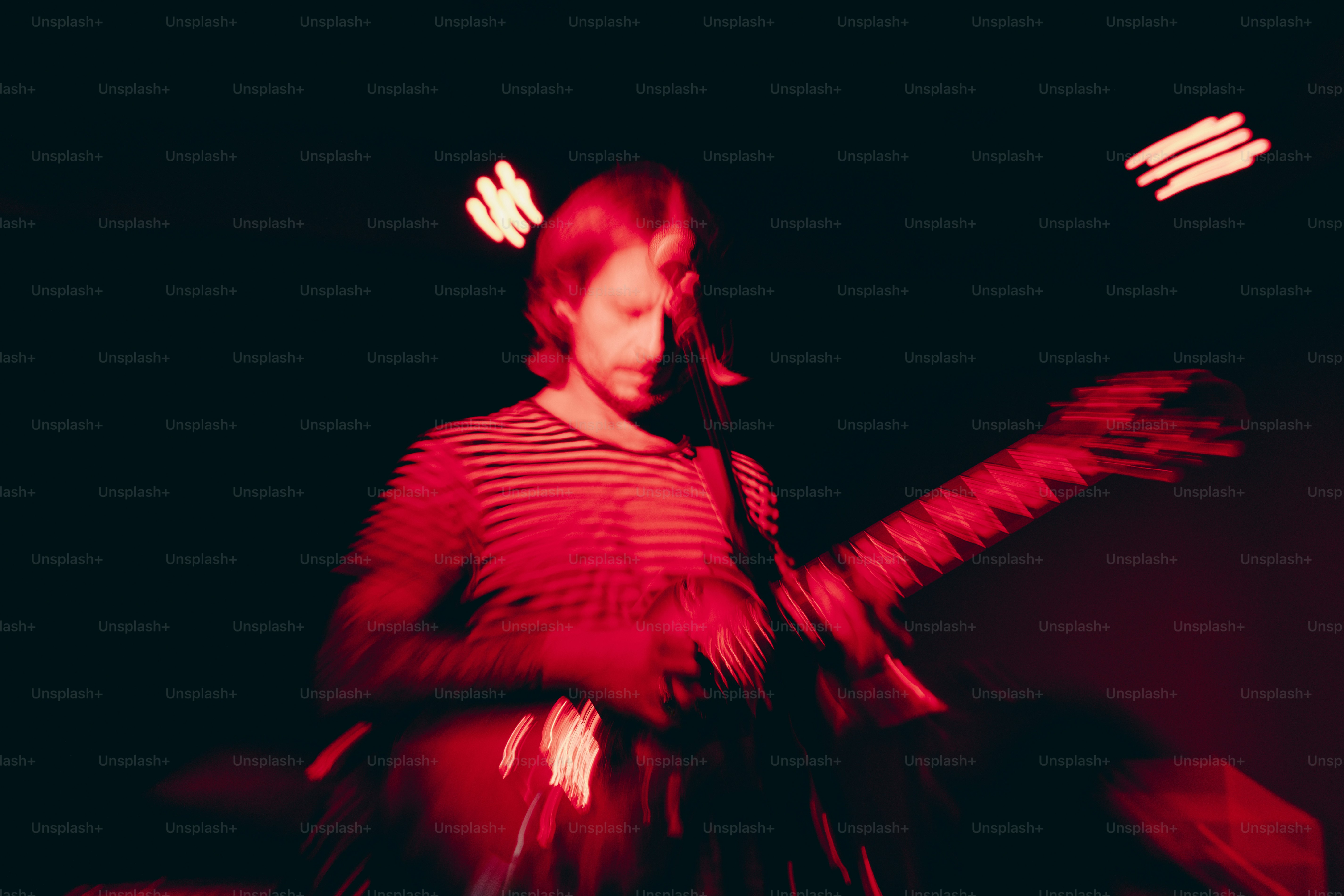 Un musicista suona la chitarra sotto l'illuminazione rossa del palco.