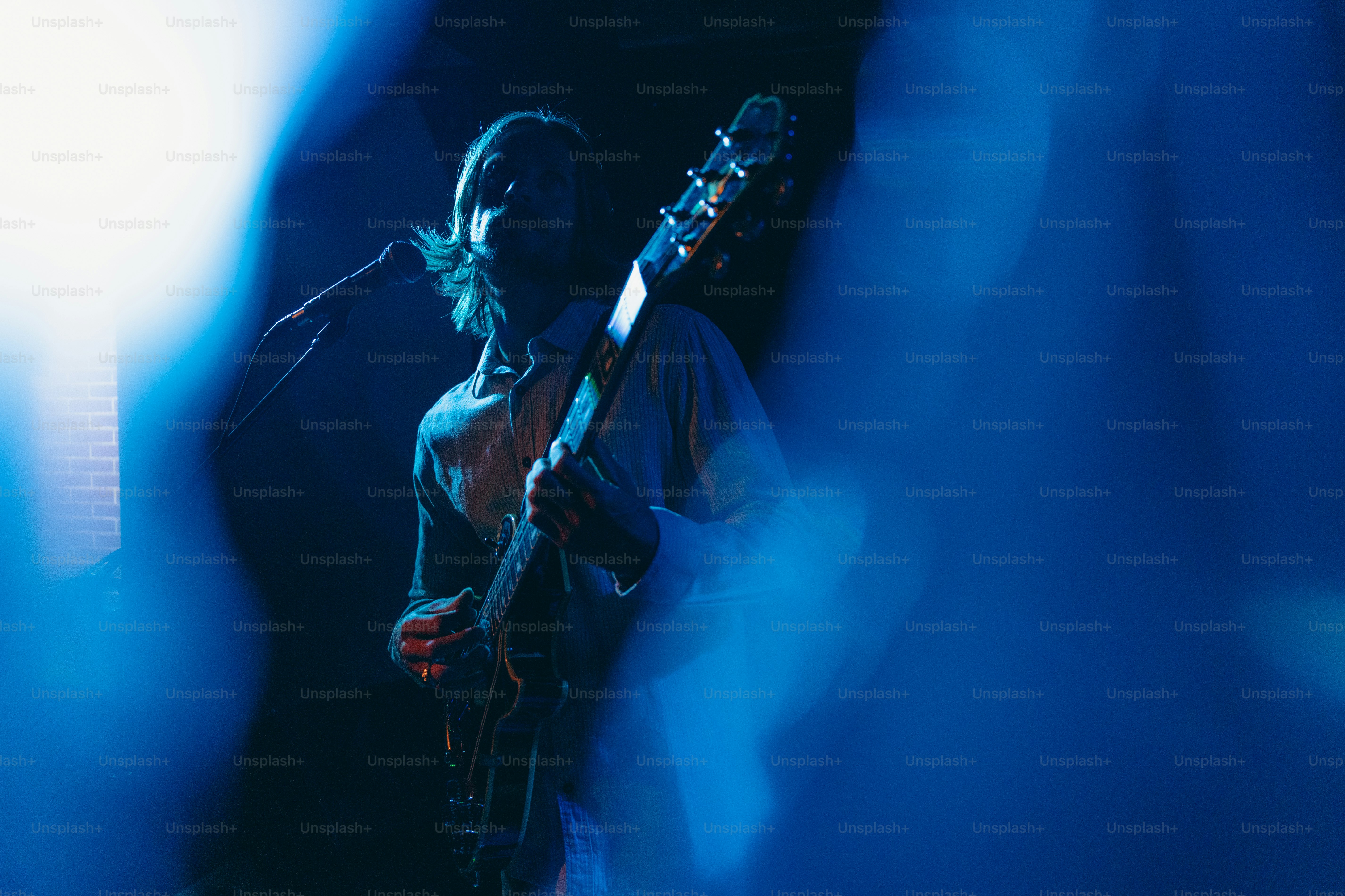 Um guitarrista se apresenta sob luzes azuis do palco.