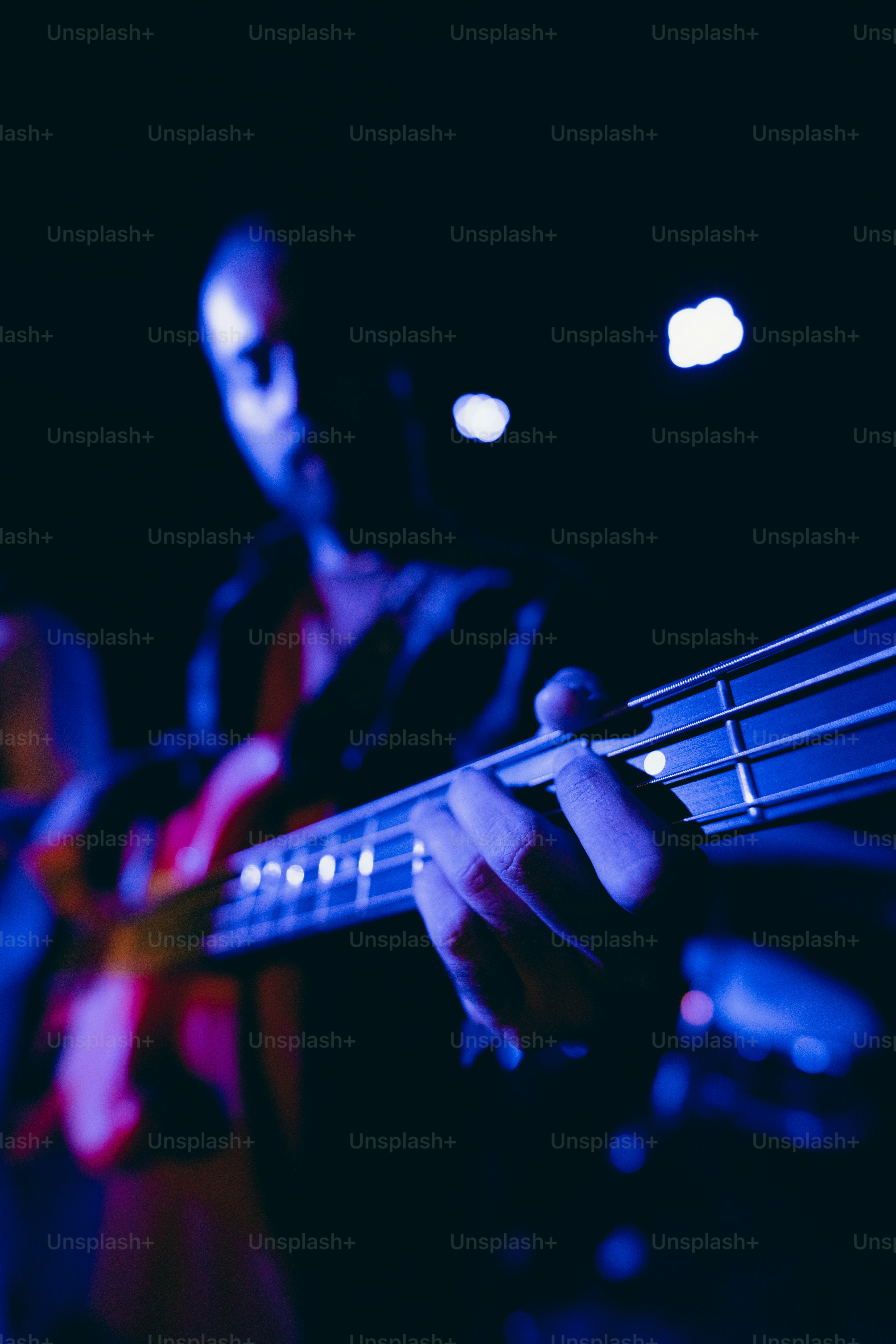 Ein Musiker spielt Bassgitarre unter blauem Licht.