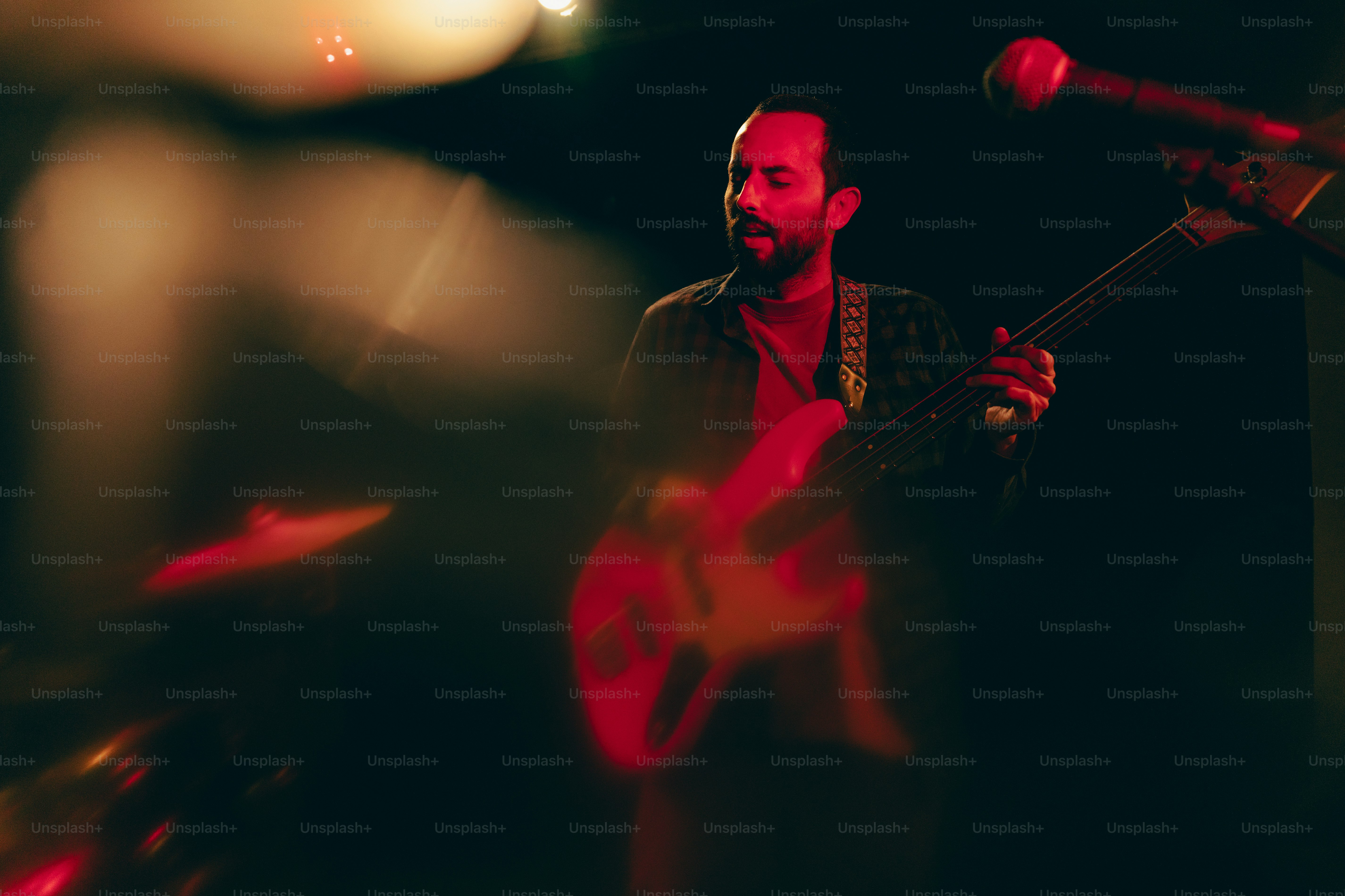 Man playing guitar on stage with lights.
