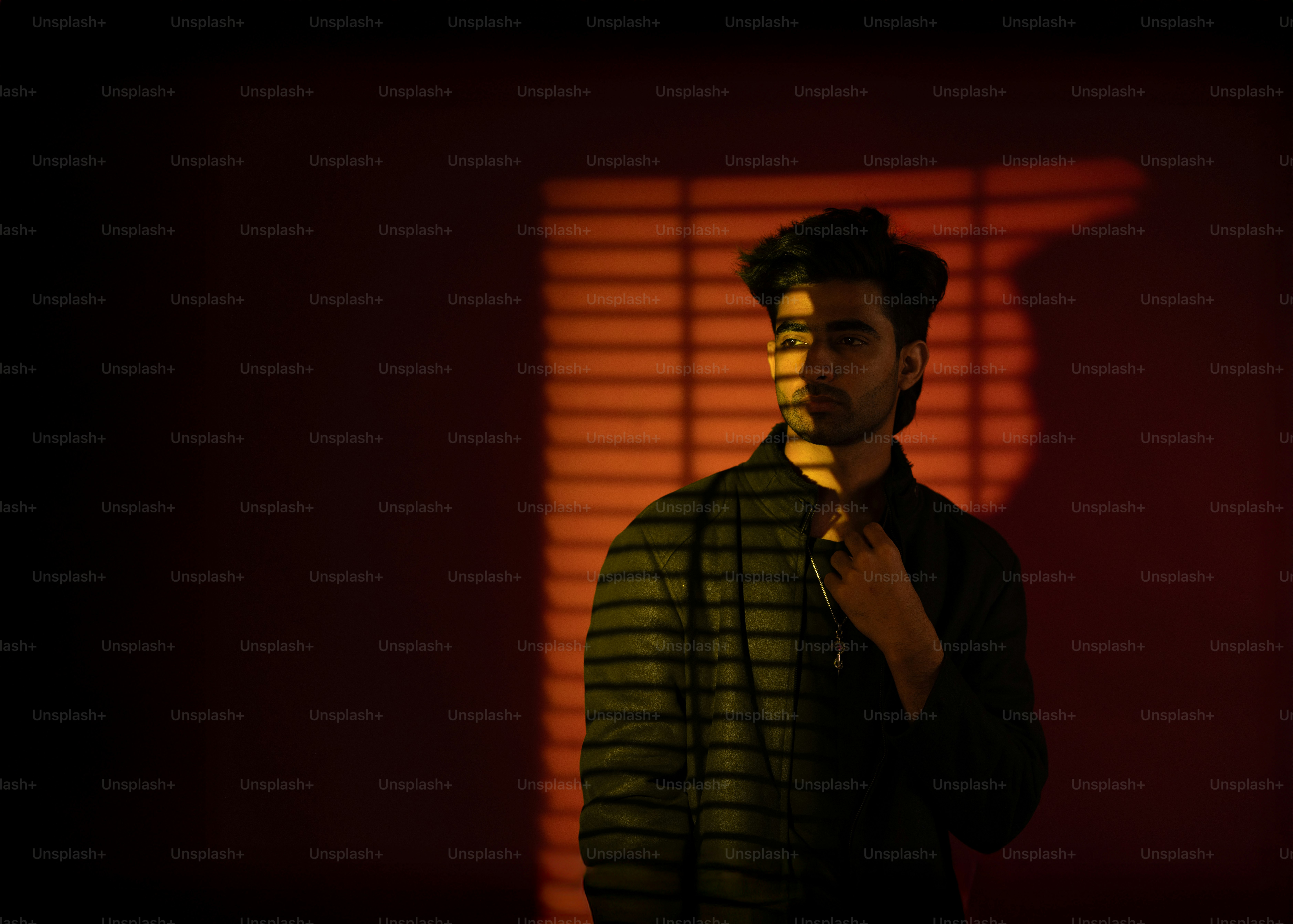 El hombre posa bajo luces y sombras cálidas.