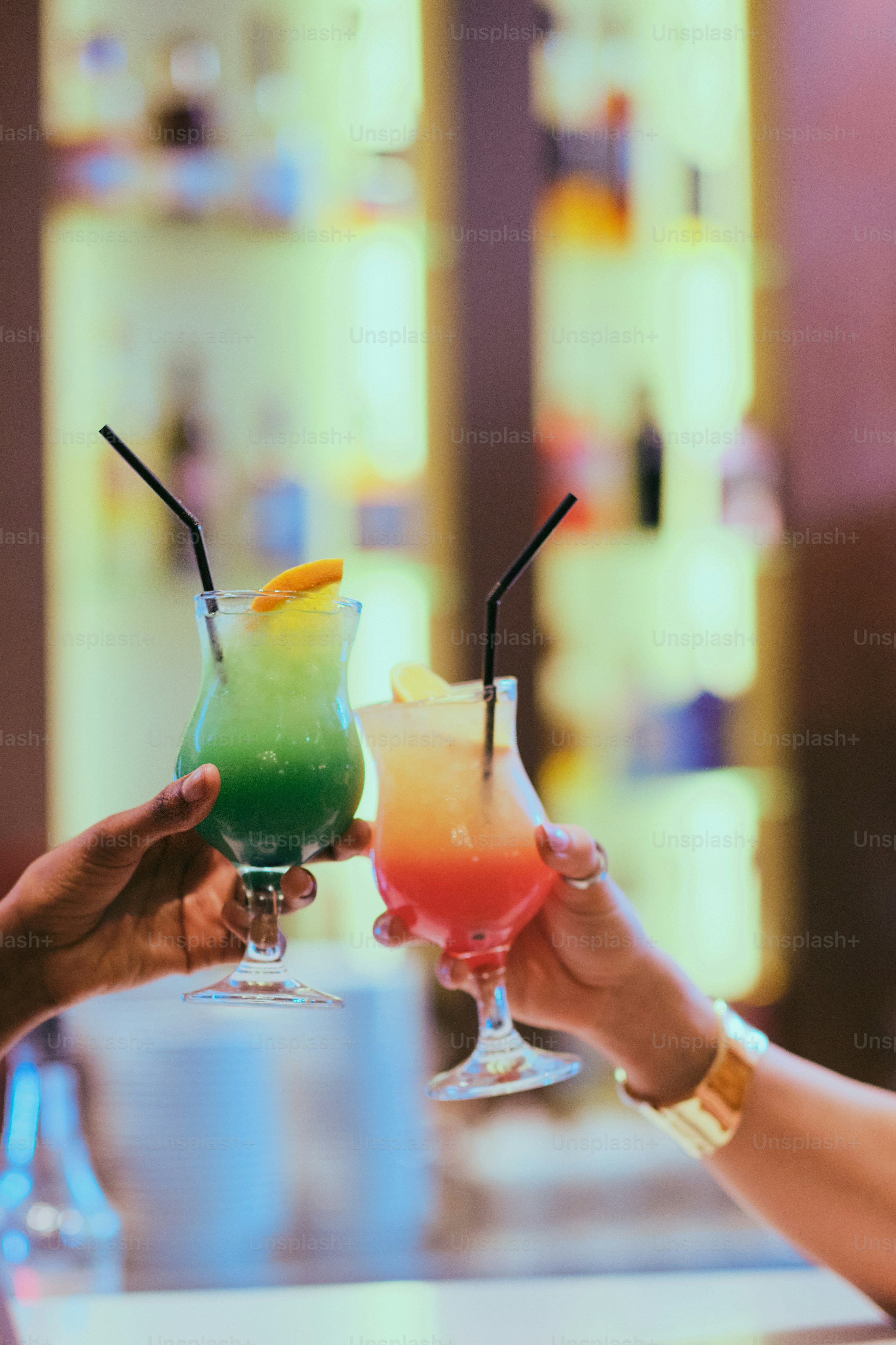 People are toasting with colorful cocktails.