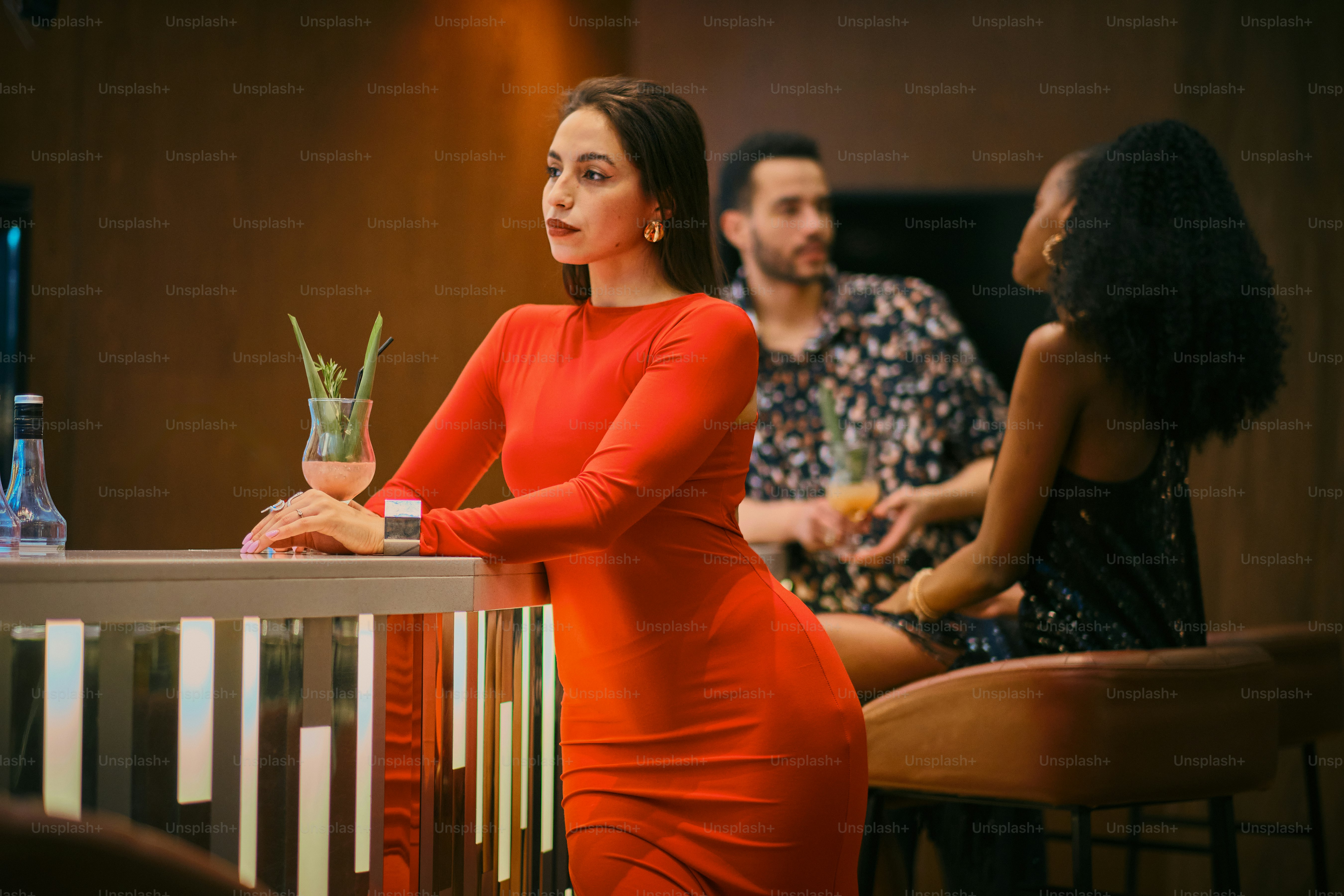 Woman in red dress at a bar, socializing.