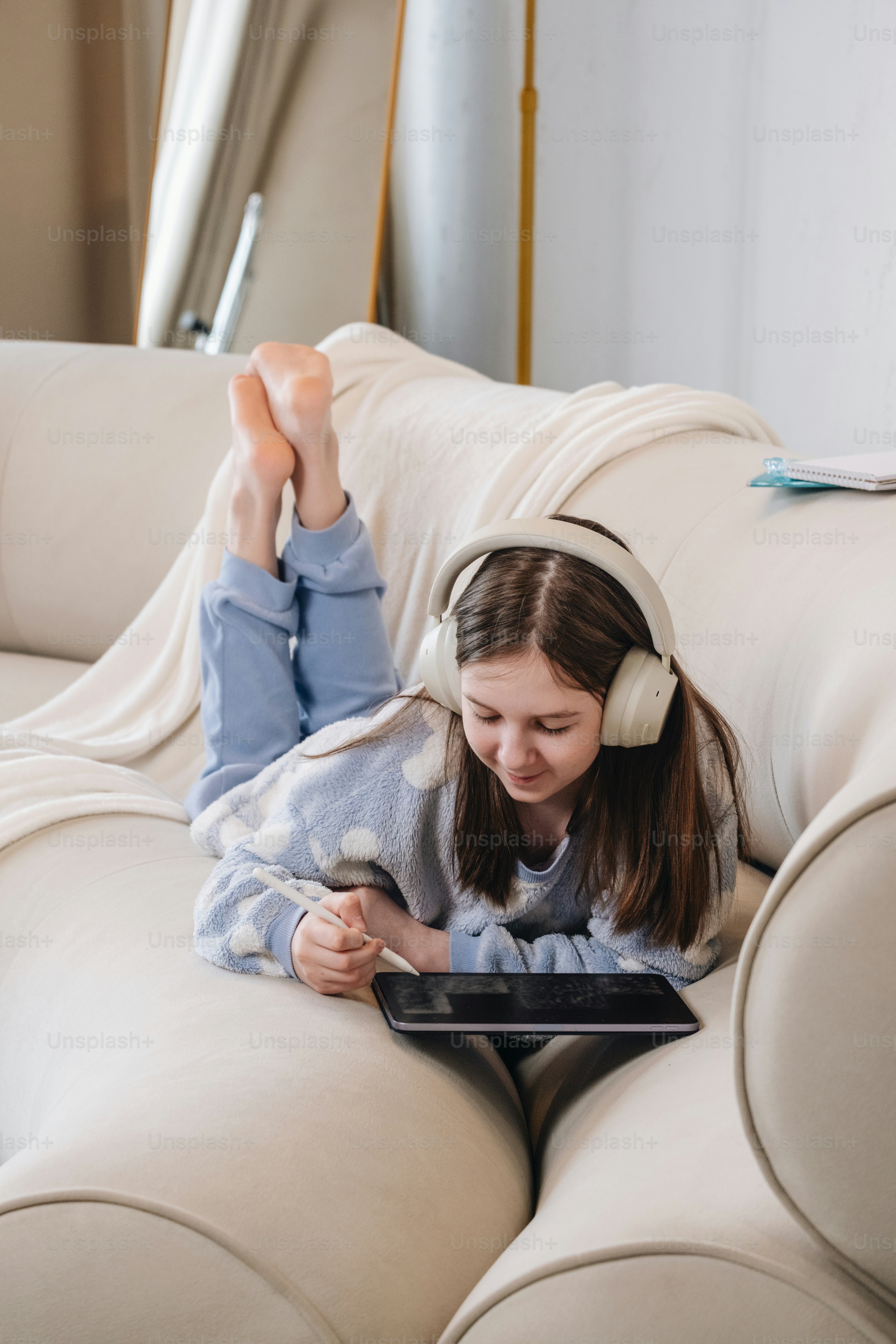 Girl relaxes on a couch while using a tablet.