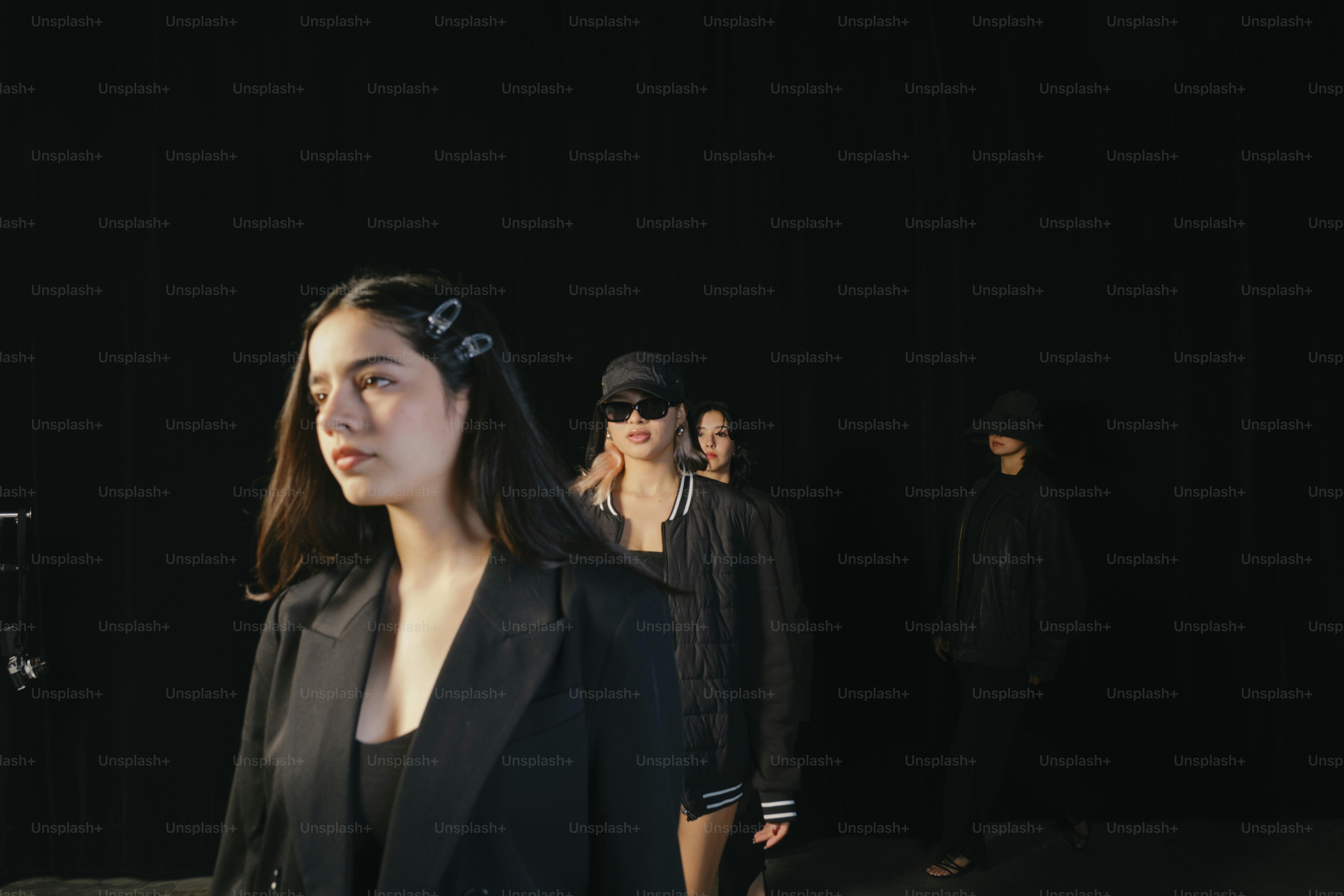 Models walk in a dark runway.