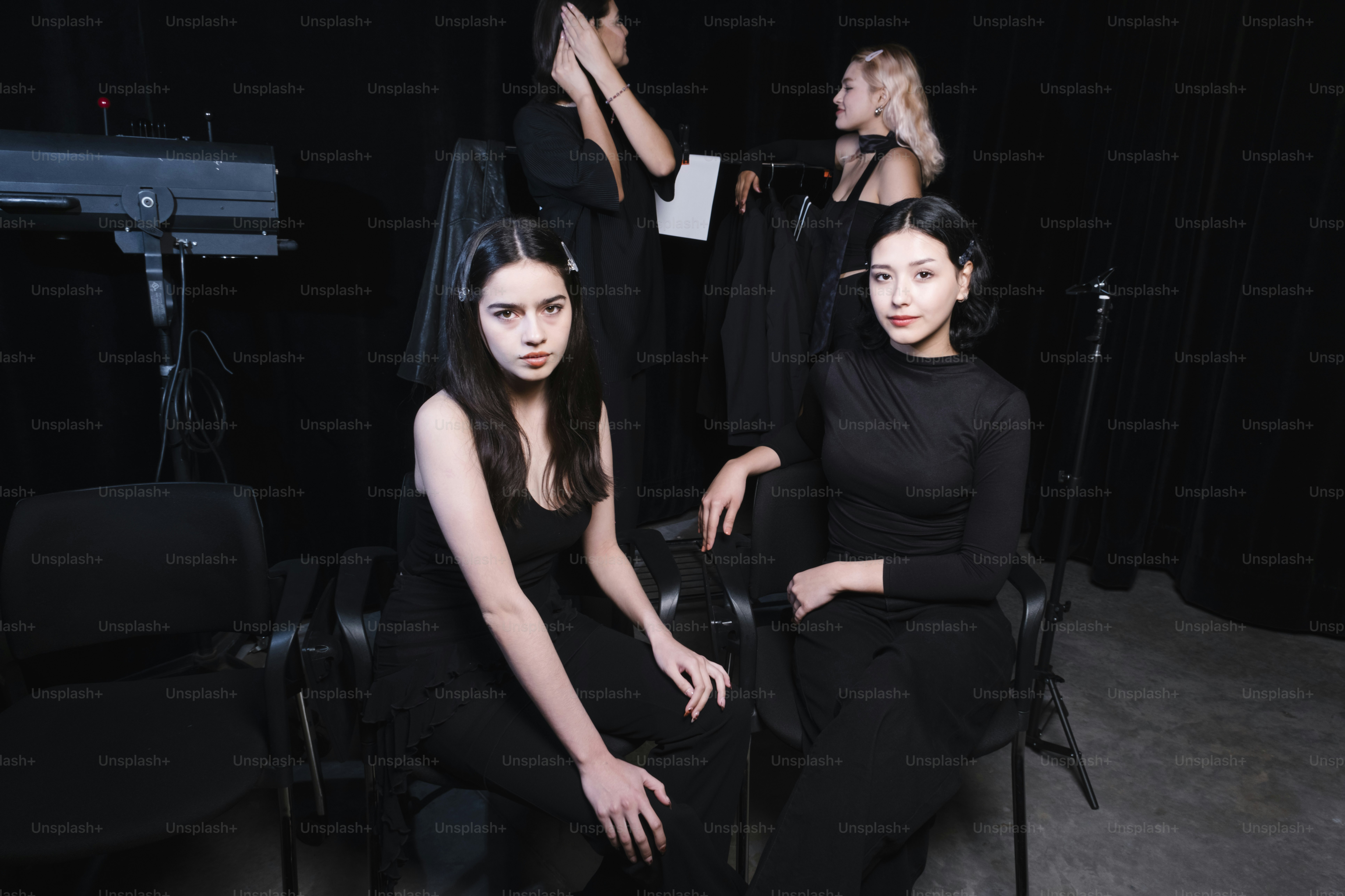 Four women pose in front of a dark background.