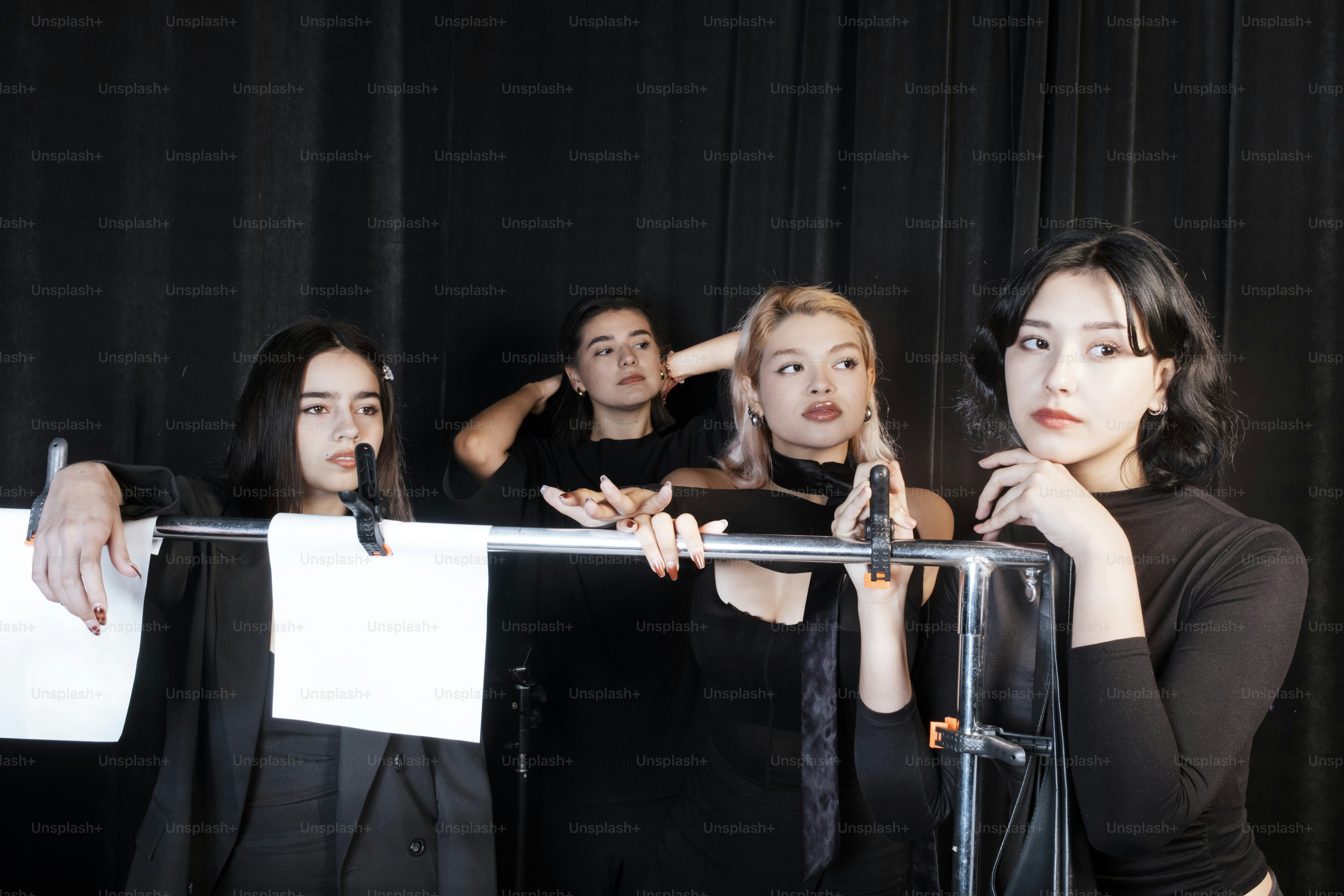 Four women are standing behind a clothes rack.