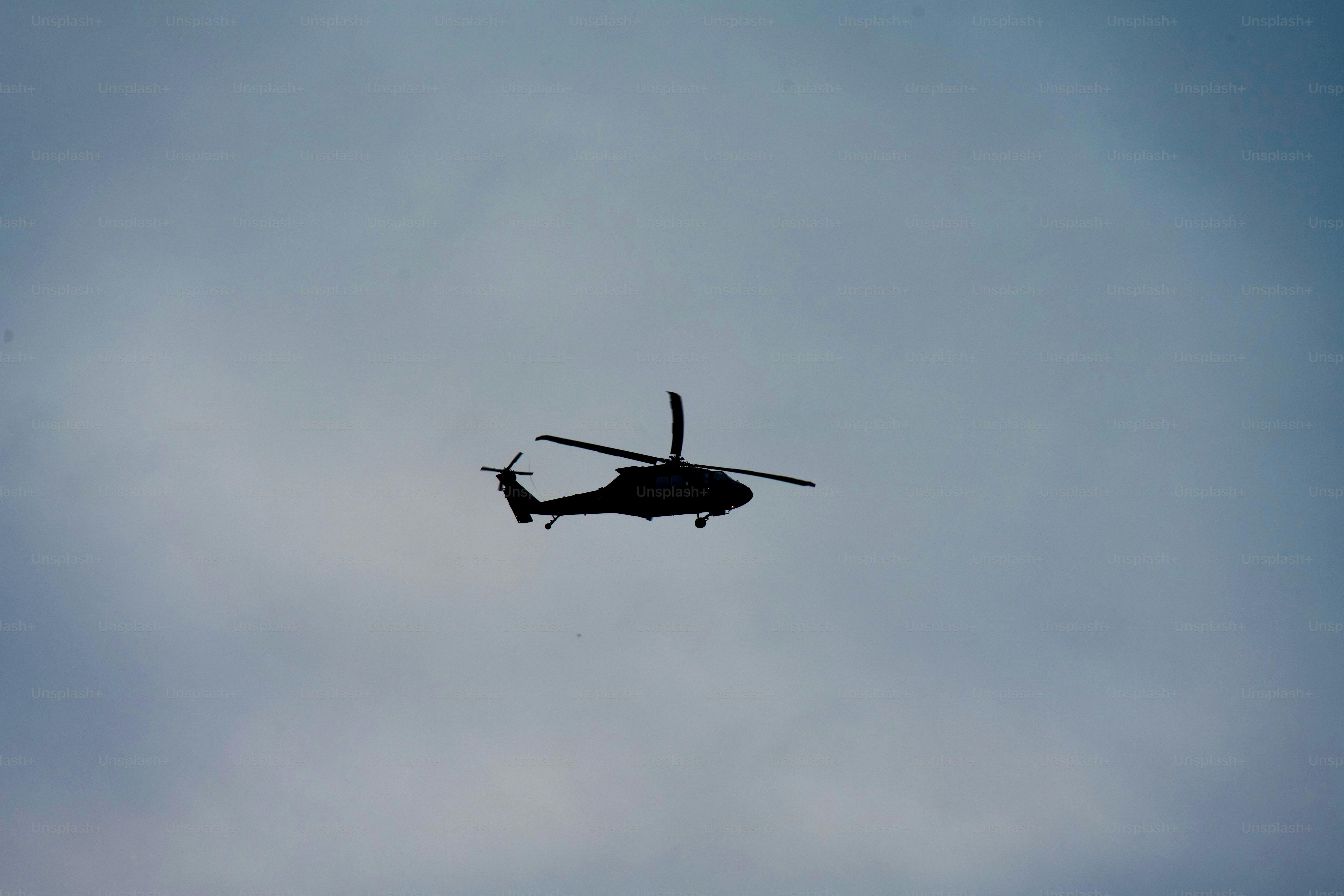 Un hélicoptère de l’armée vole à basse altitude par un après-midi nuageux.