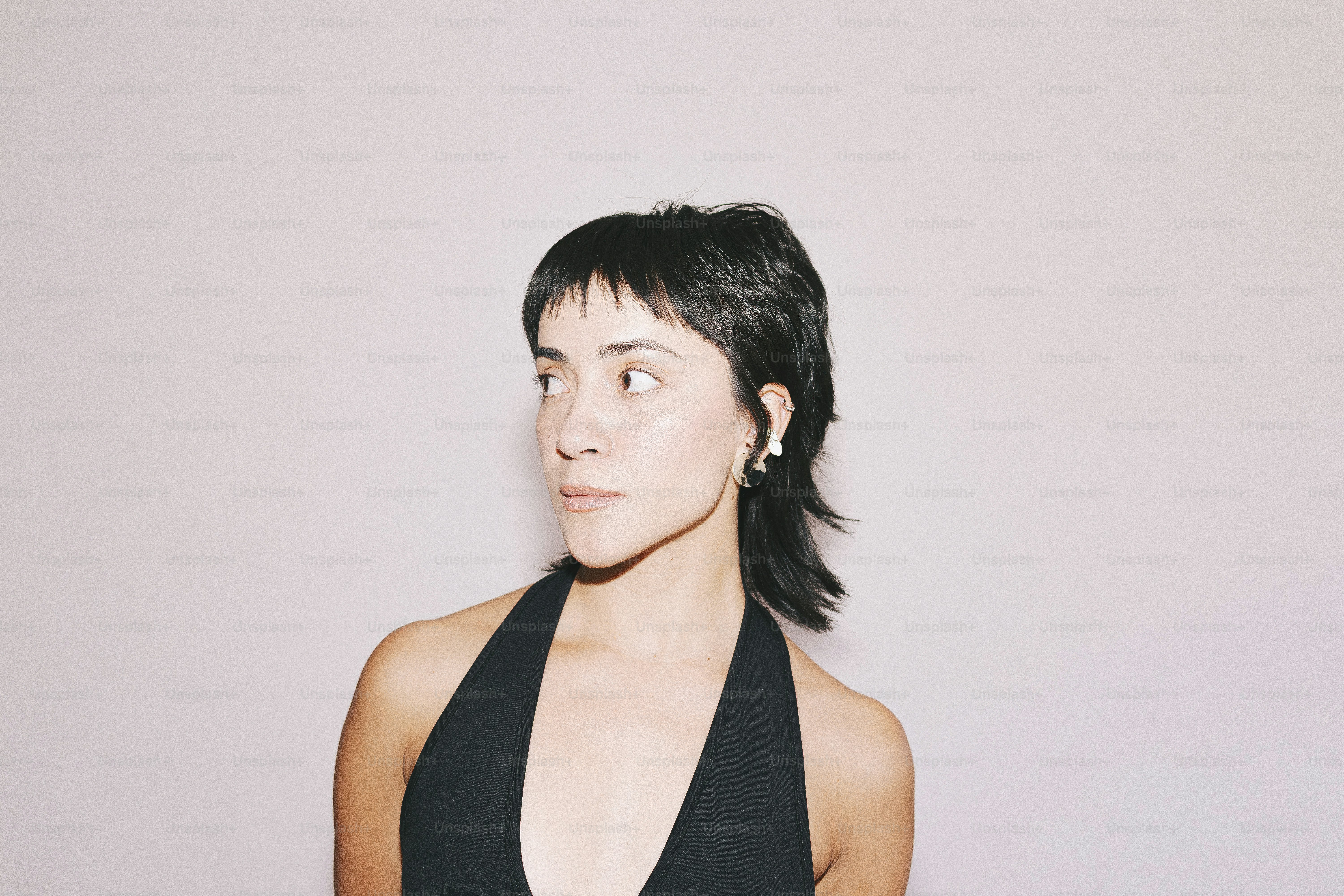 A woman poses, wearing a black halter top.