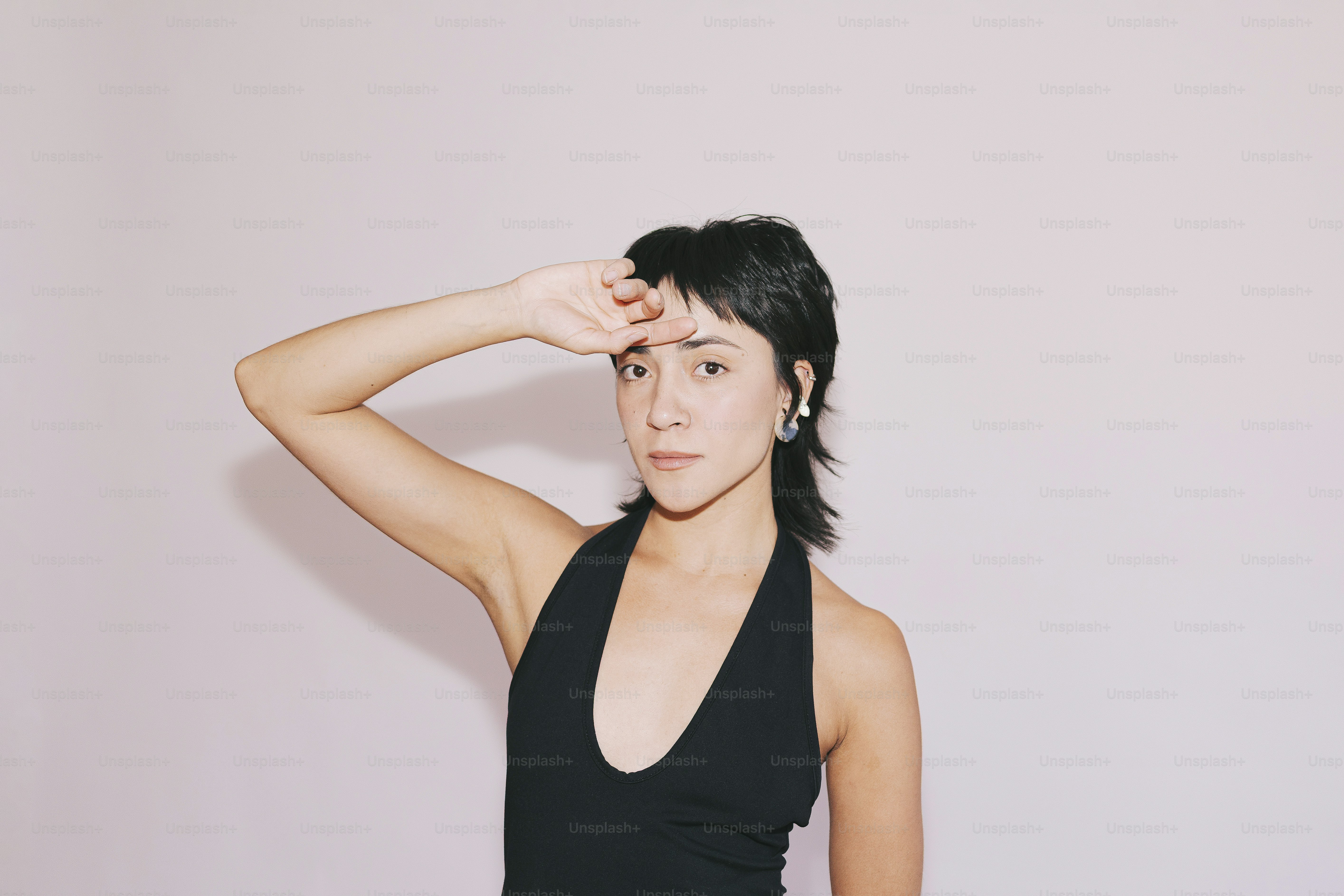 Woman poses with hand above her face.