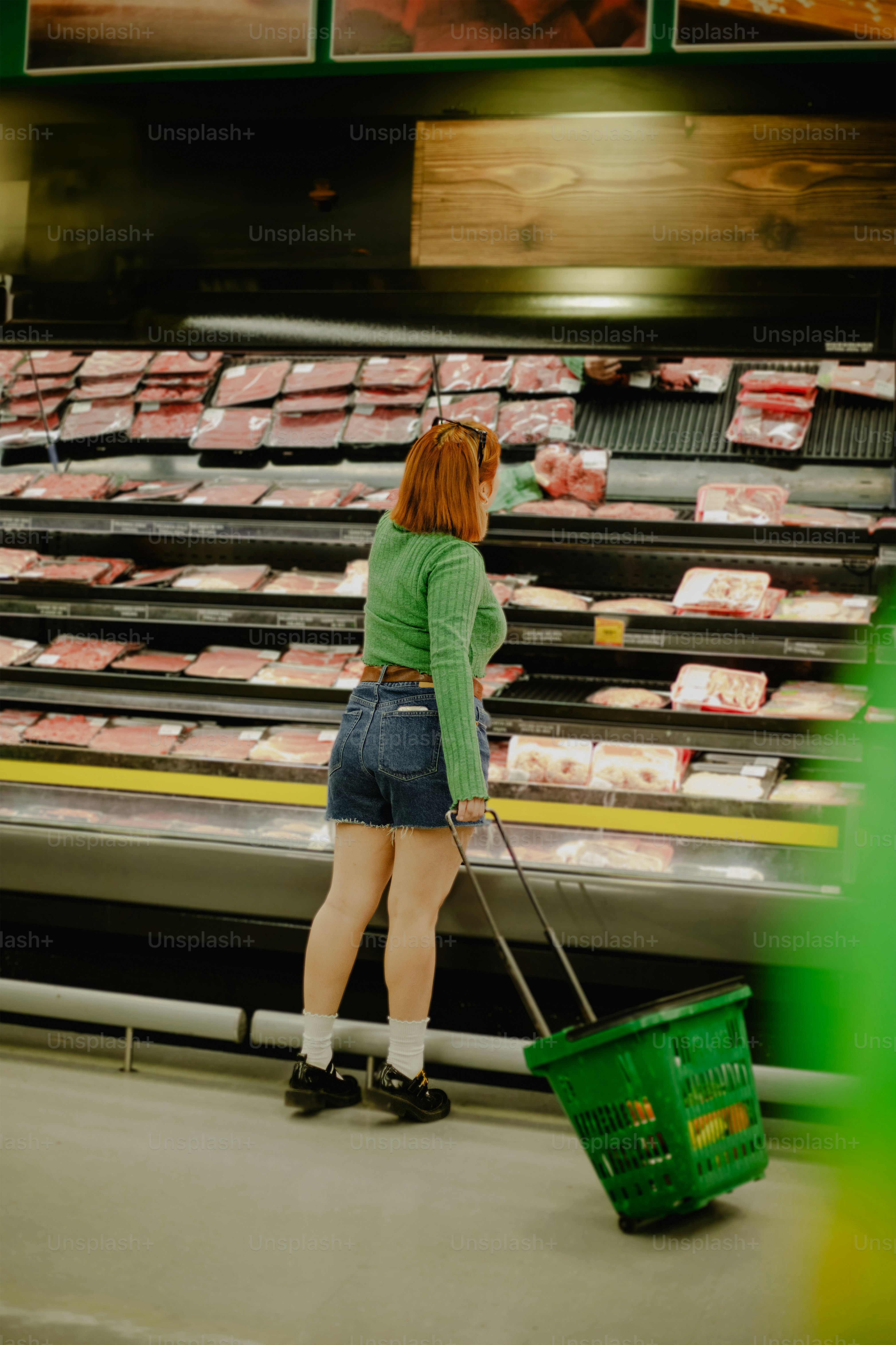 A woman shops for meat in the grocery store.