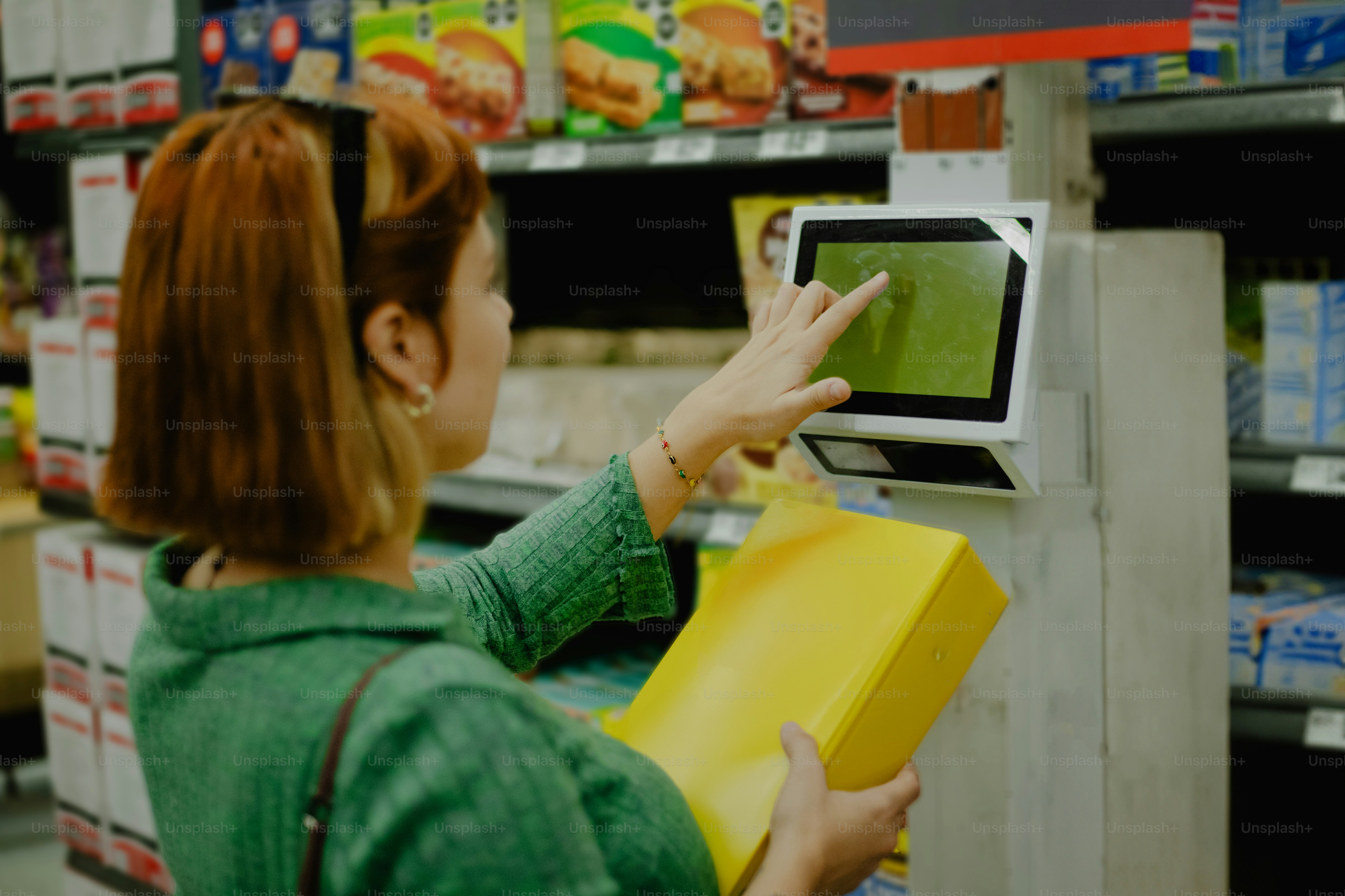 A woman uses a touchscreen in a grocery store.