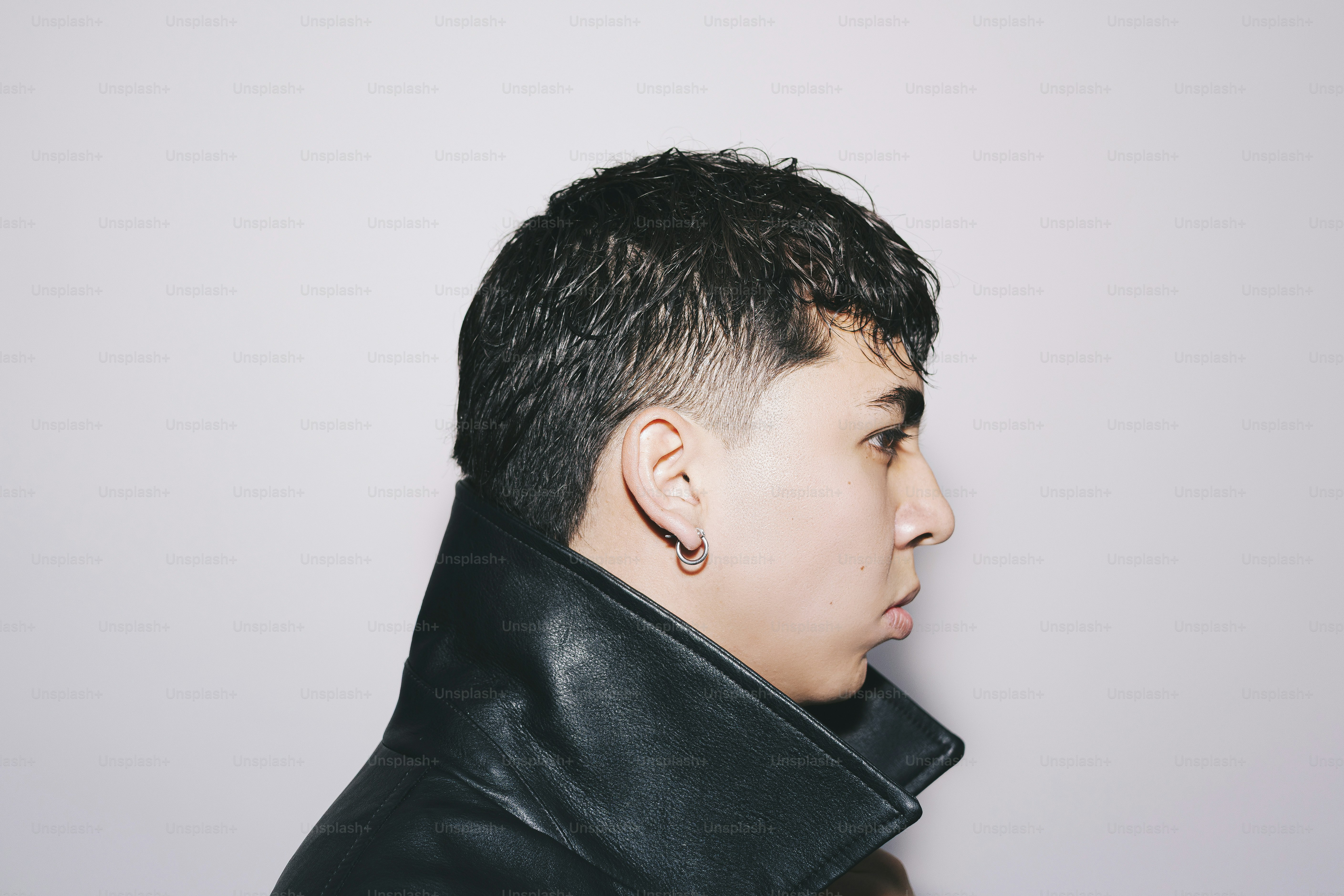 A man poses in profile against a white backdrop.