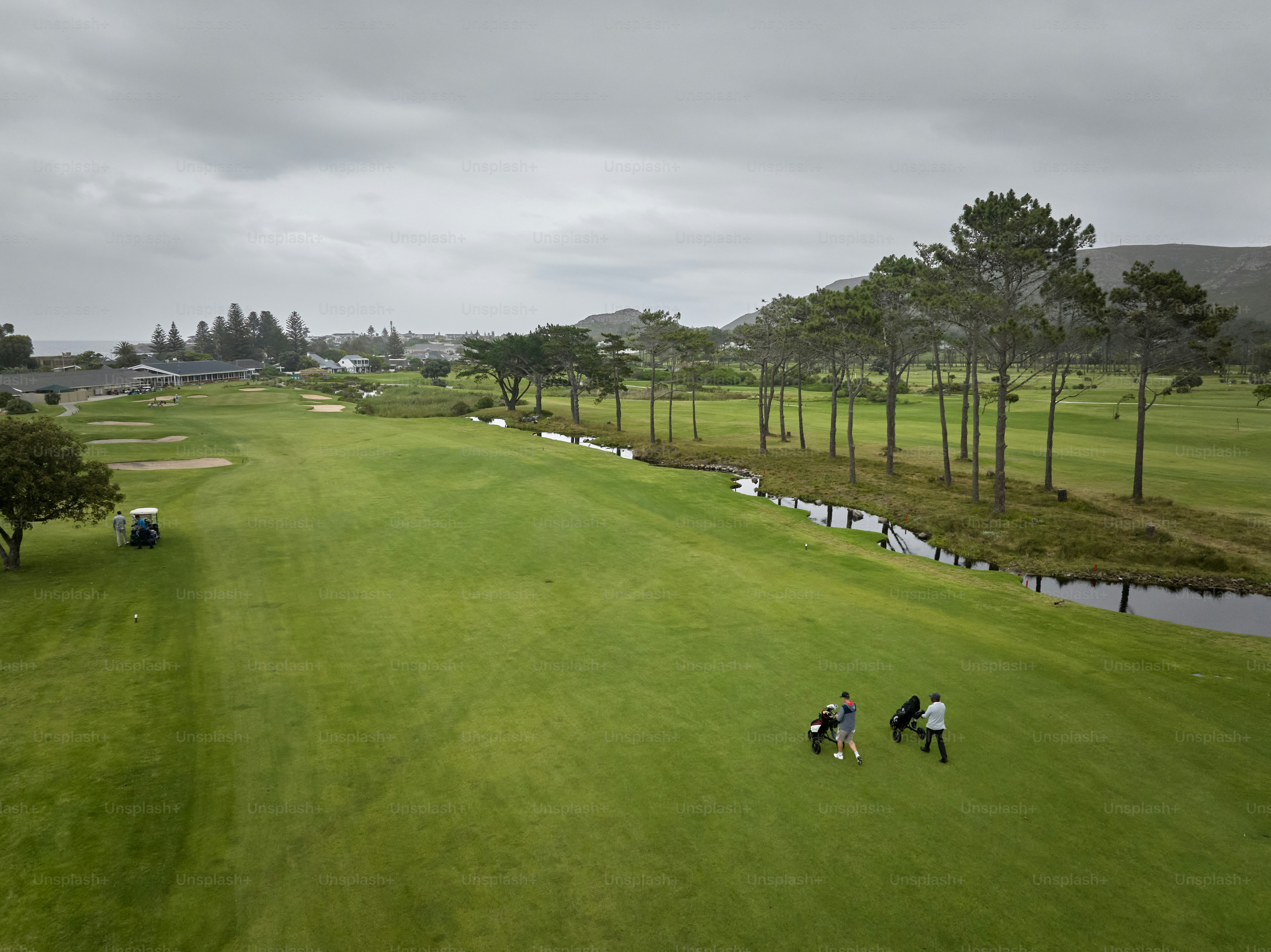 Aerial via of a group of senior golfers walking down the fairway on a cloudy day at a beautiful golf course