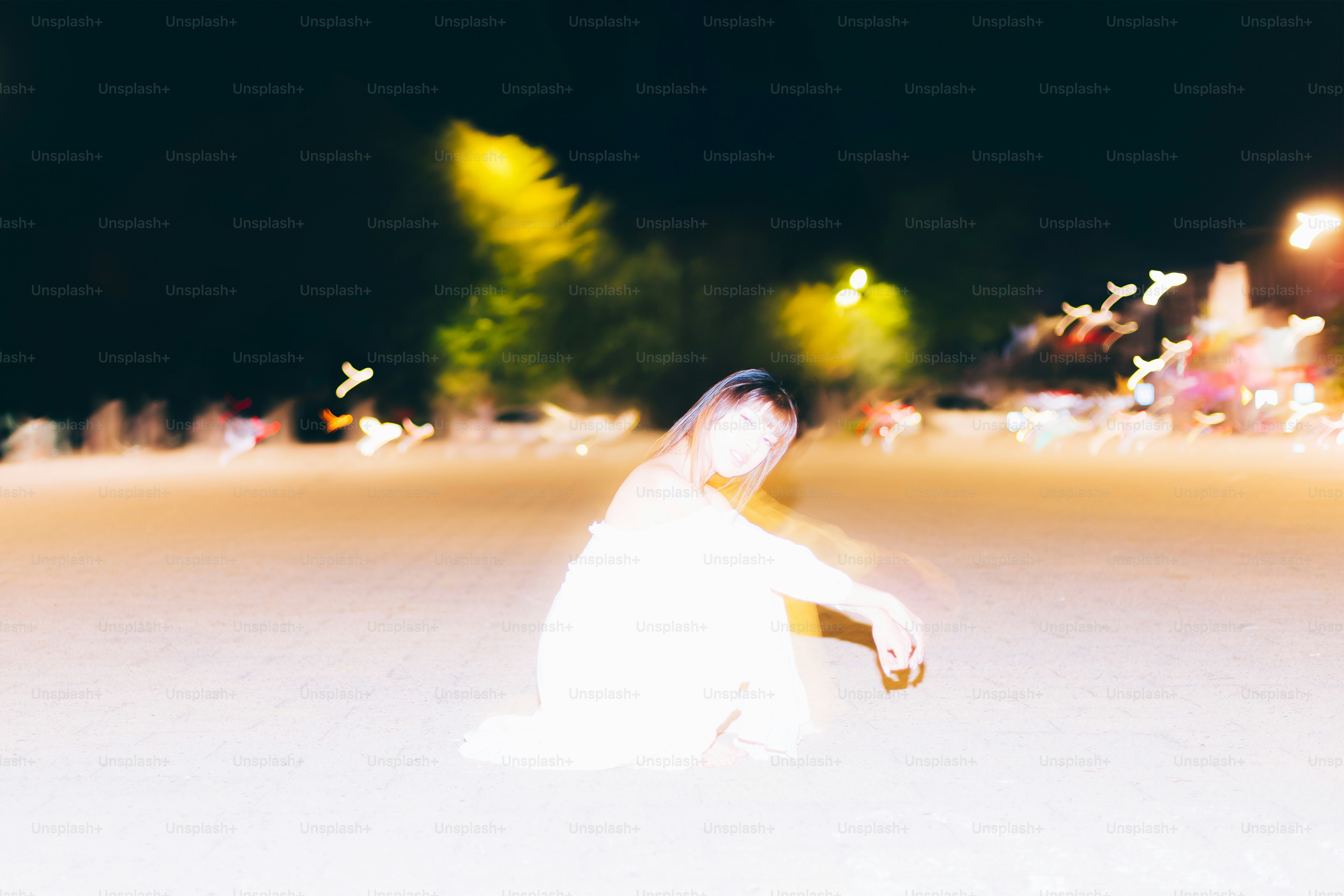 A blurry figure kneels outdoors at night.