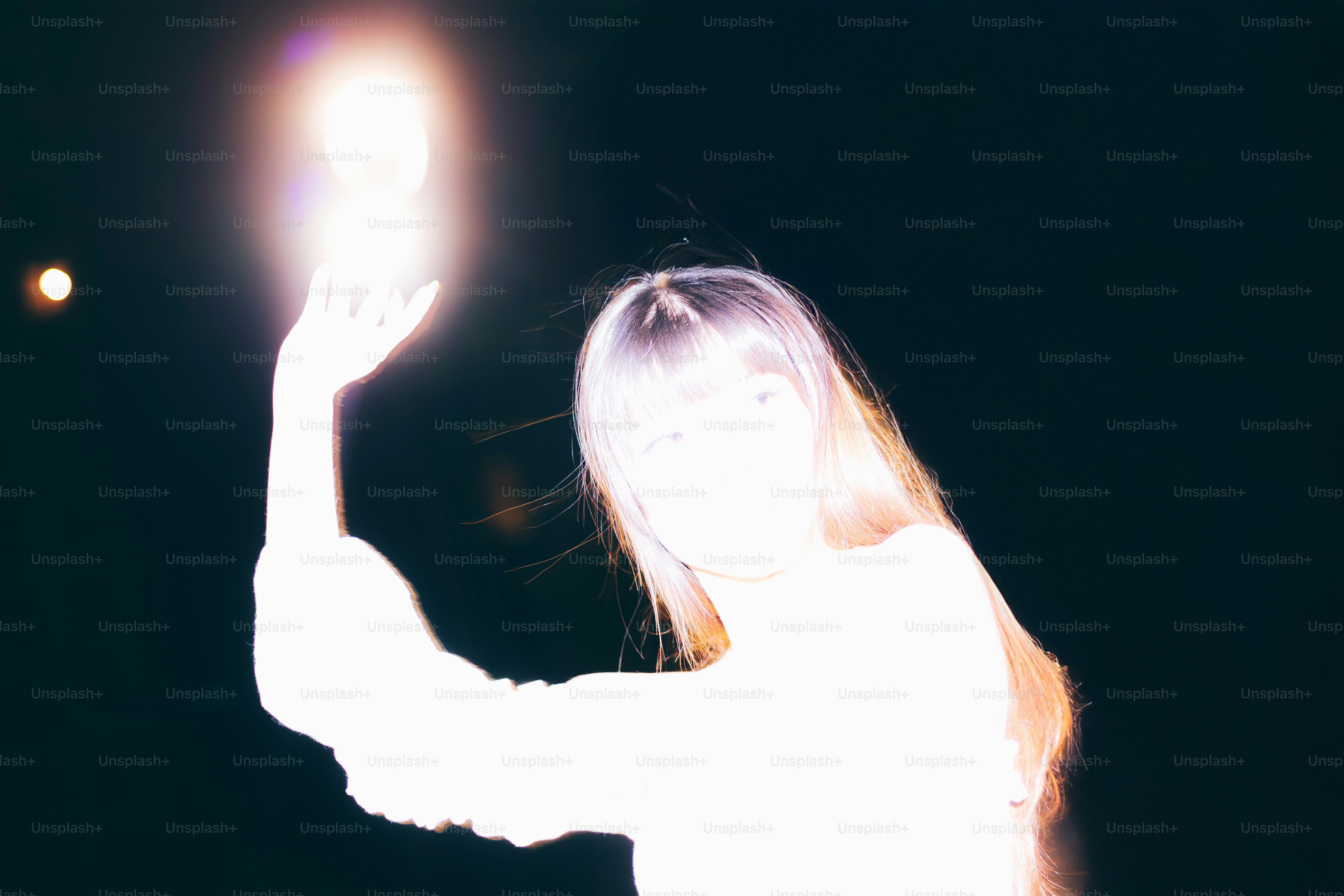 A woman holds up a glowing light orb.