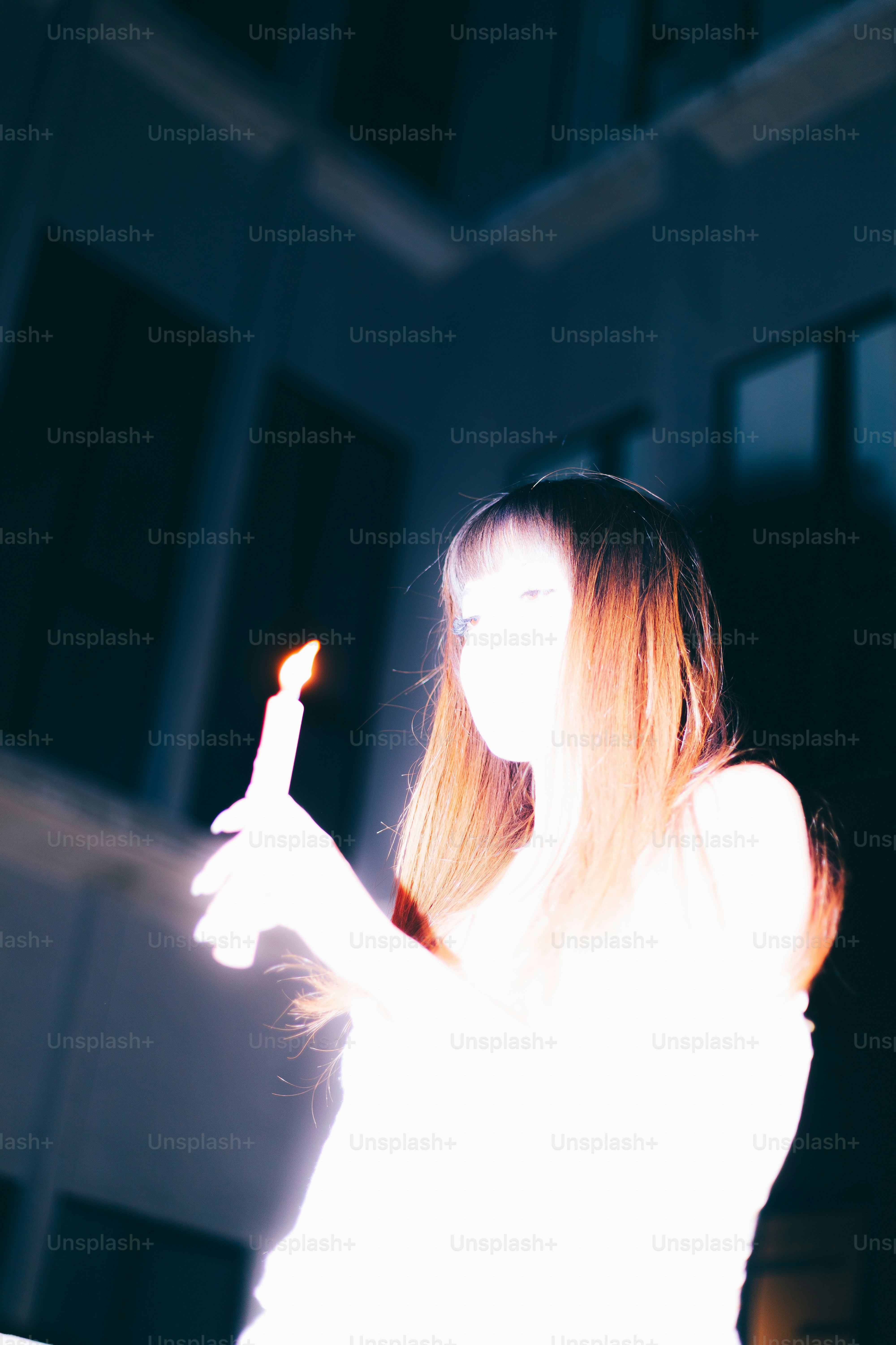 Eine Frau hält eine Kerze in einer schummrigen Umgebung.