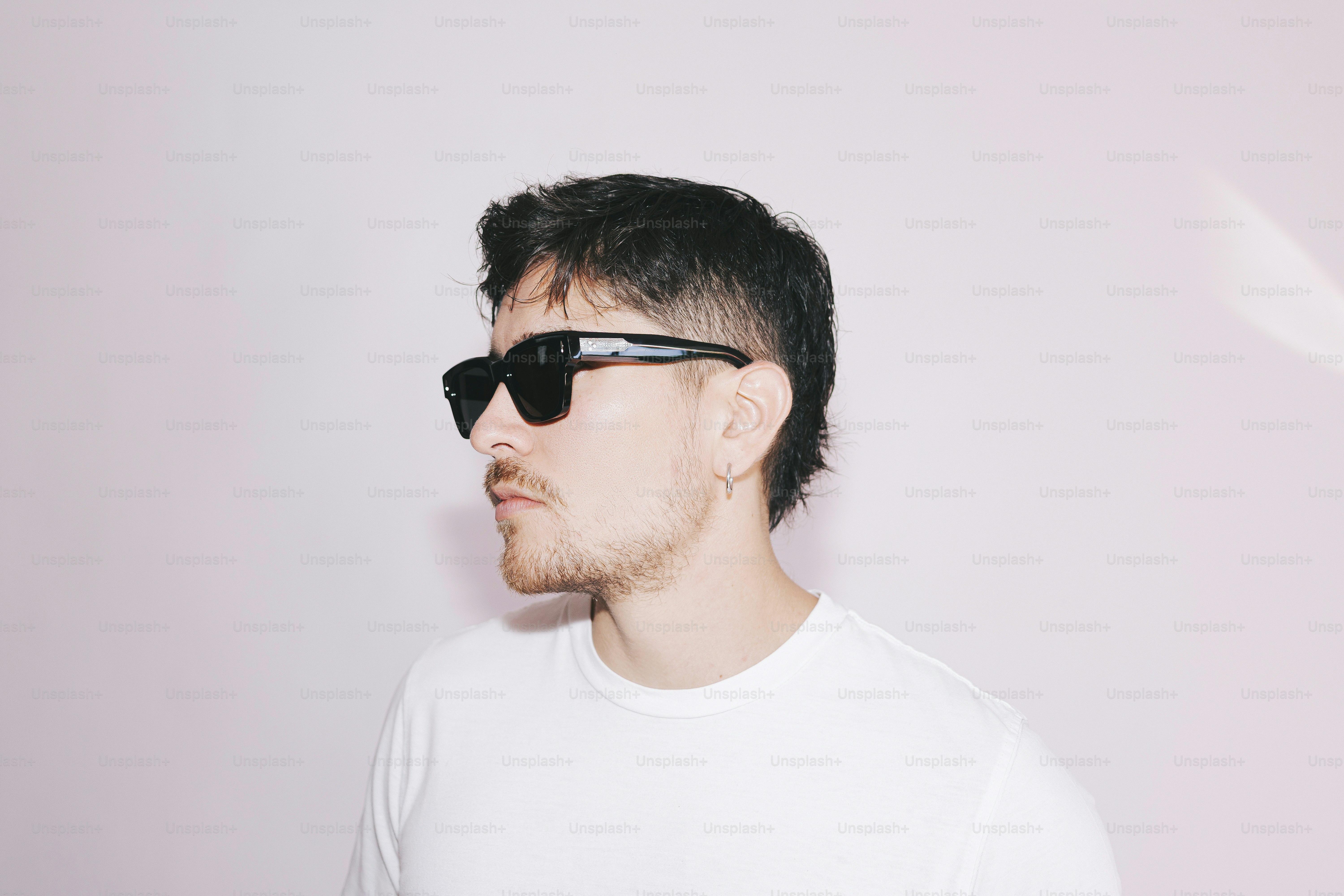 Un uomo che indossa occhiali da sole e una camicia bianca.