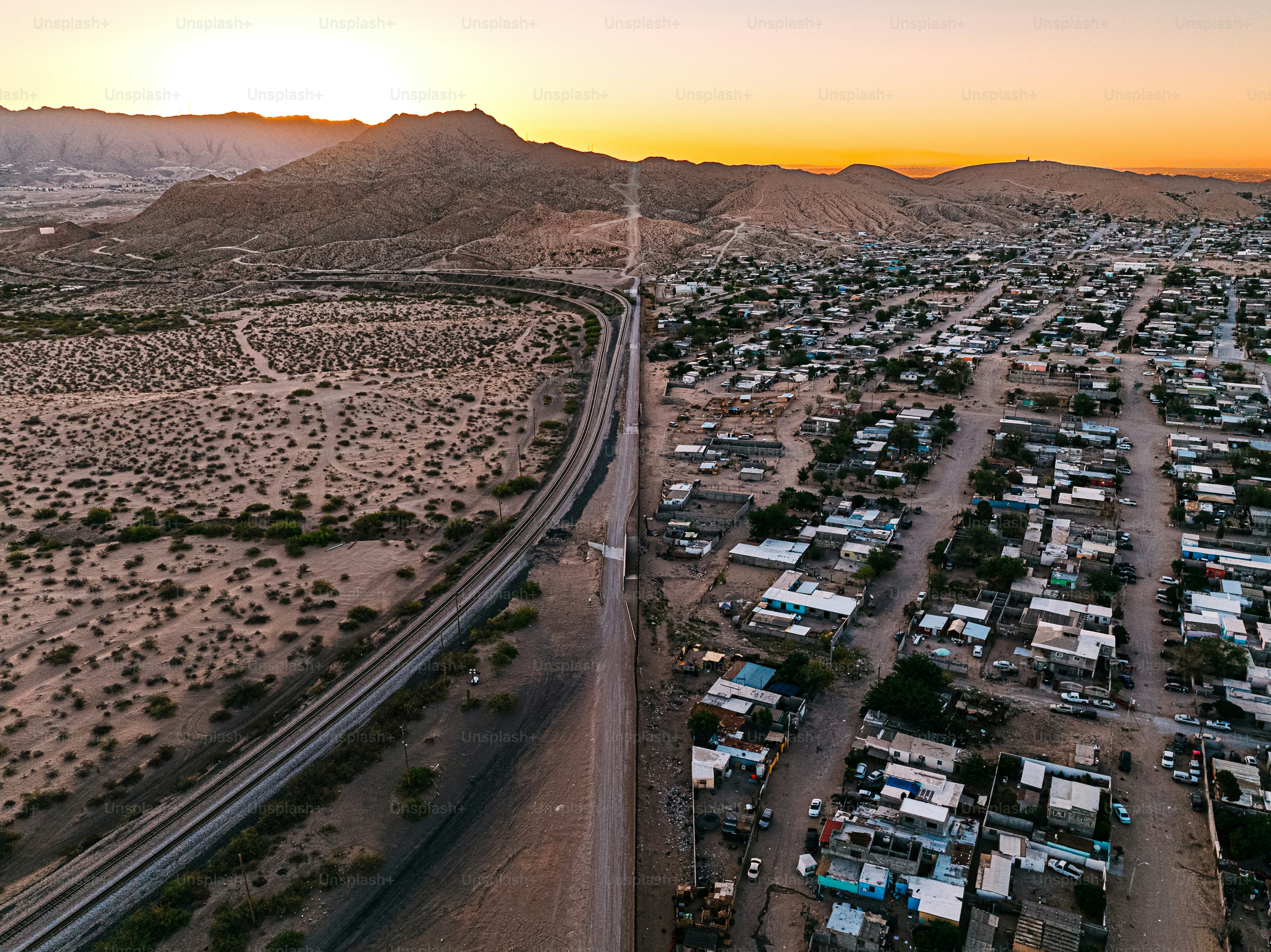 Aerial View of the U.S. Southern Border Wall Fence, (“El Muro Fronterizo,”) separating El Paso and Ciudad Juárez, Mexico in Springtime. The railroad track supports trade between Mexico and the USA. 

Photo taken in the United States.