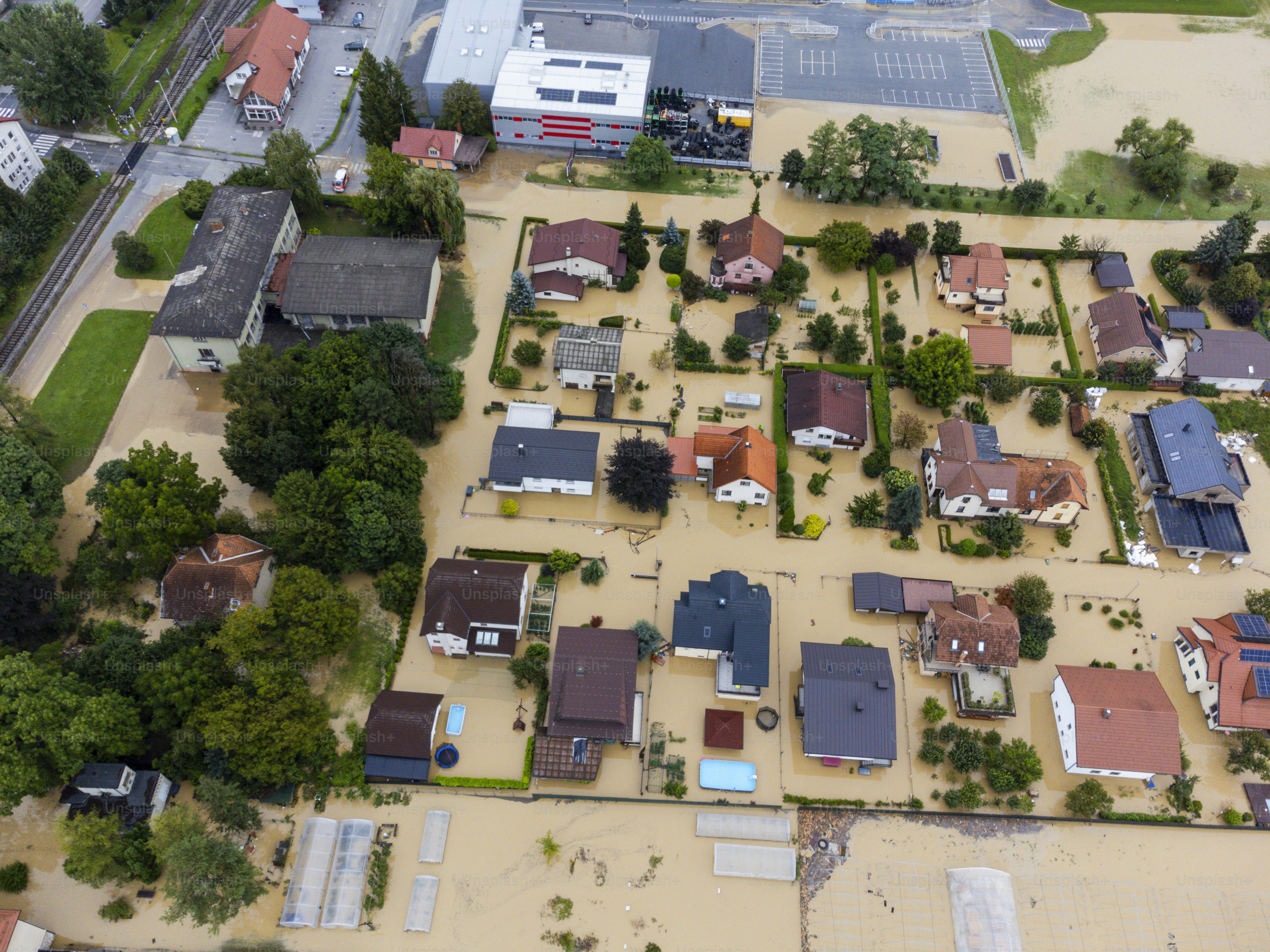 Aerial view of a flooded residential area with submerged streets and houses, showcasing the impact of natural disasters on a community. Location: Zalec, Slovenia