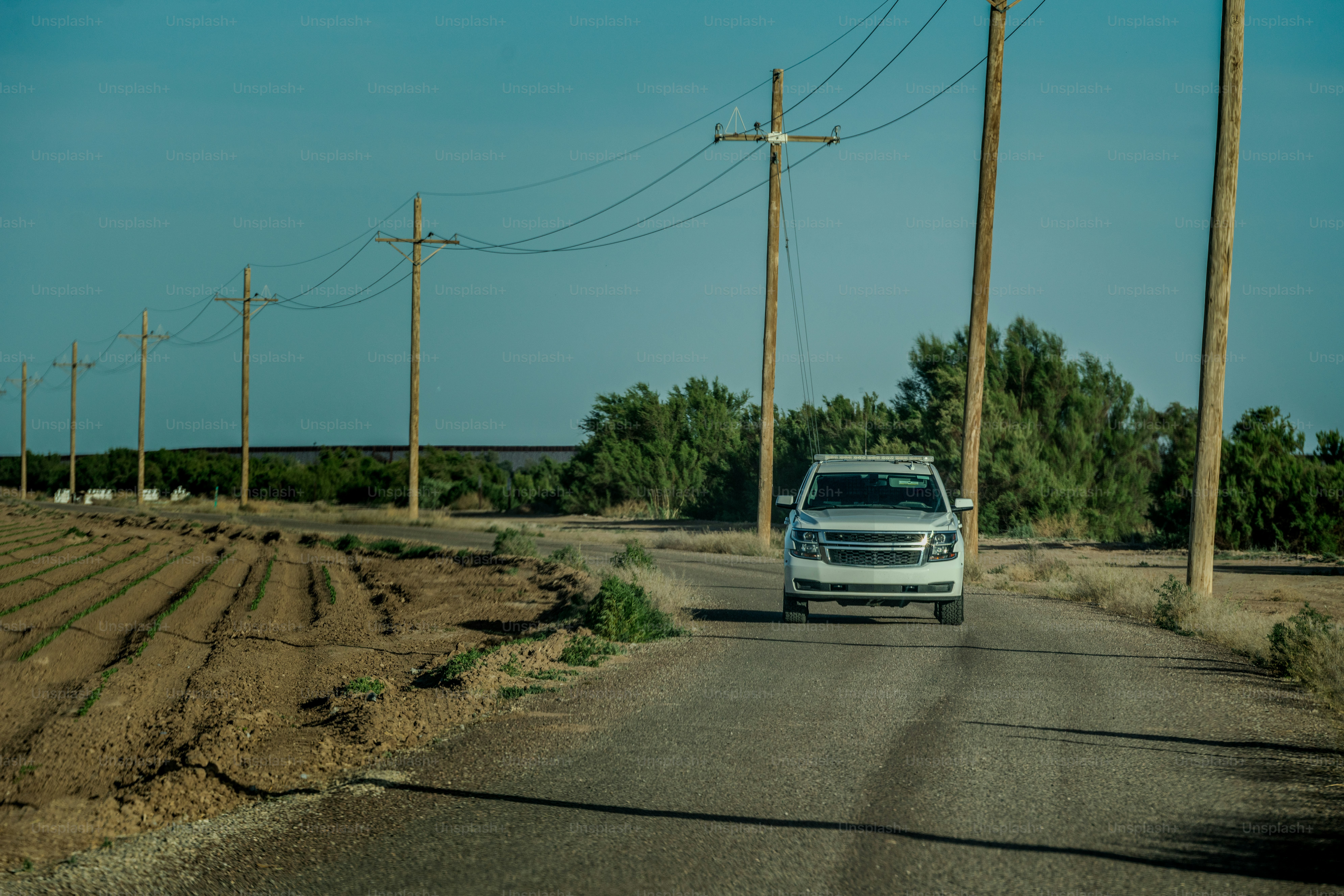 A Border Patrol Vehicle Parked, Stands Watch at the Mexican American Border Wall on a Sunny Day in the Desert Landscape Outside of El Paso Texas