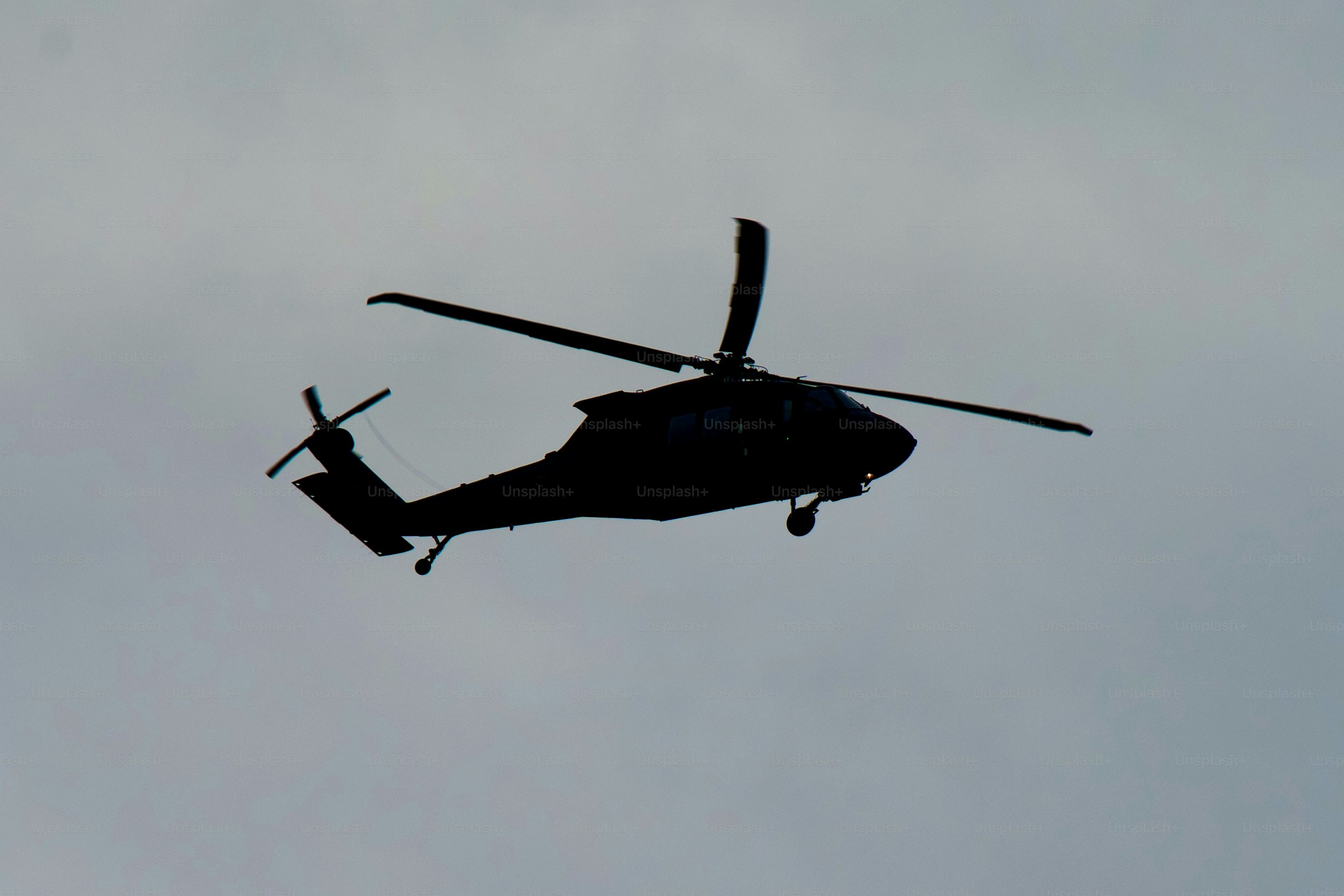 Un hélicoptère de l’armée vole à basse altitude par un après-midi nuageux.