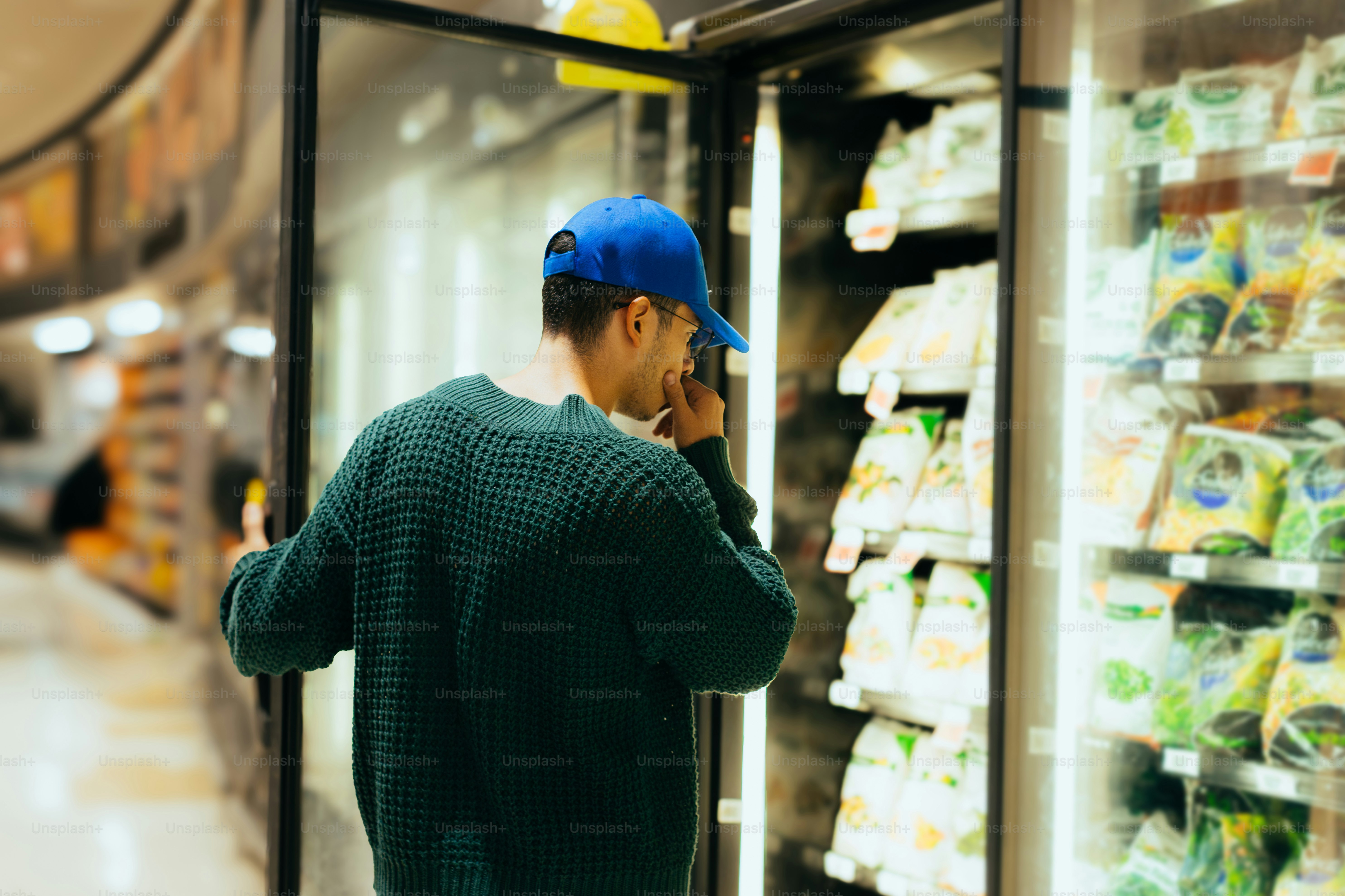 A person shops for frozen foods in a grocery store.