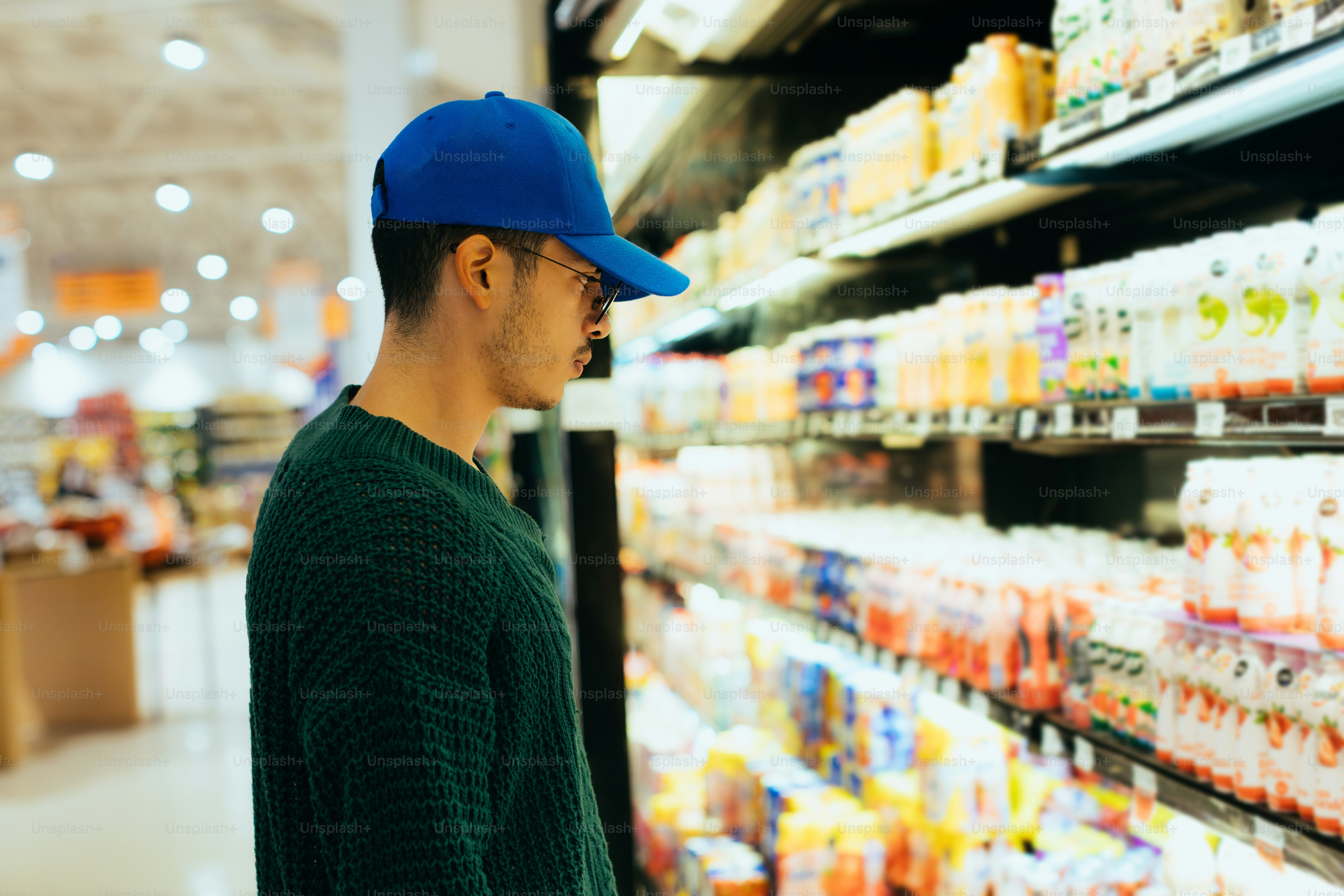 Man with a blue cap browsing supermarket shelves.