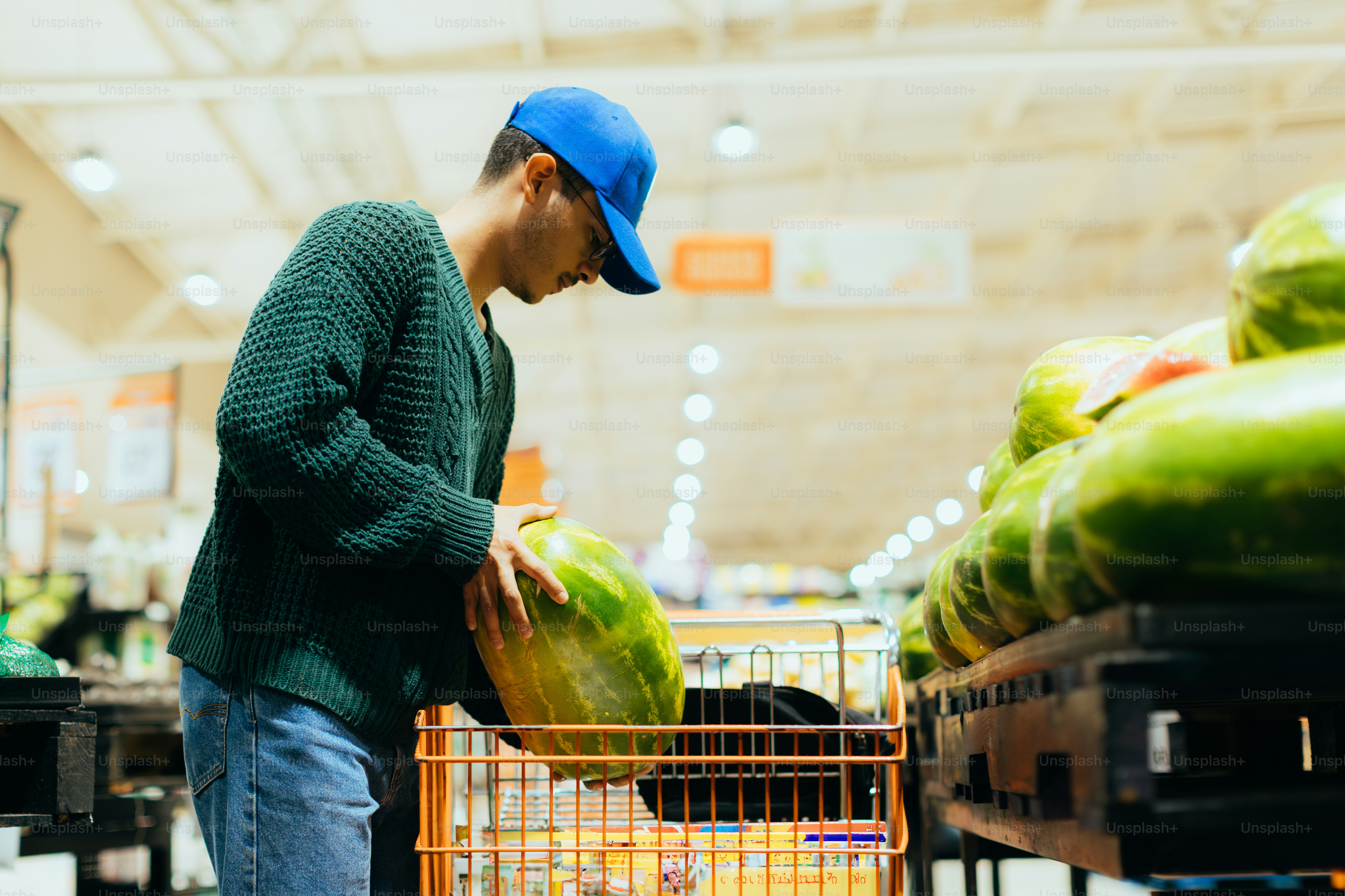 A man picks a watermelon at the grocery store.