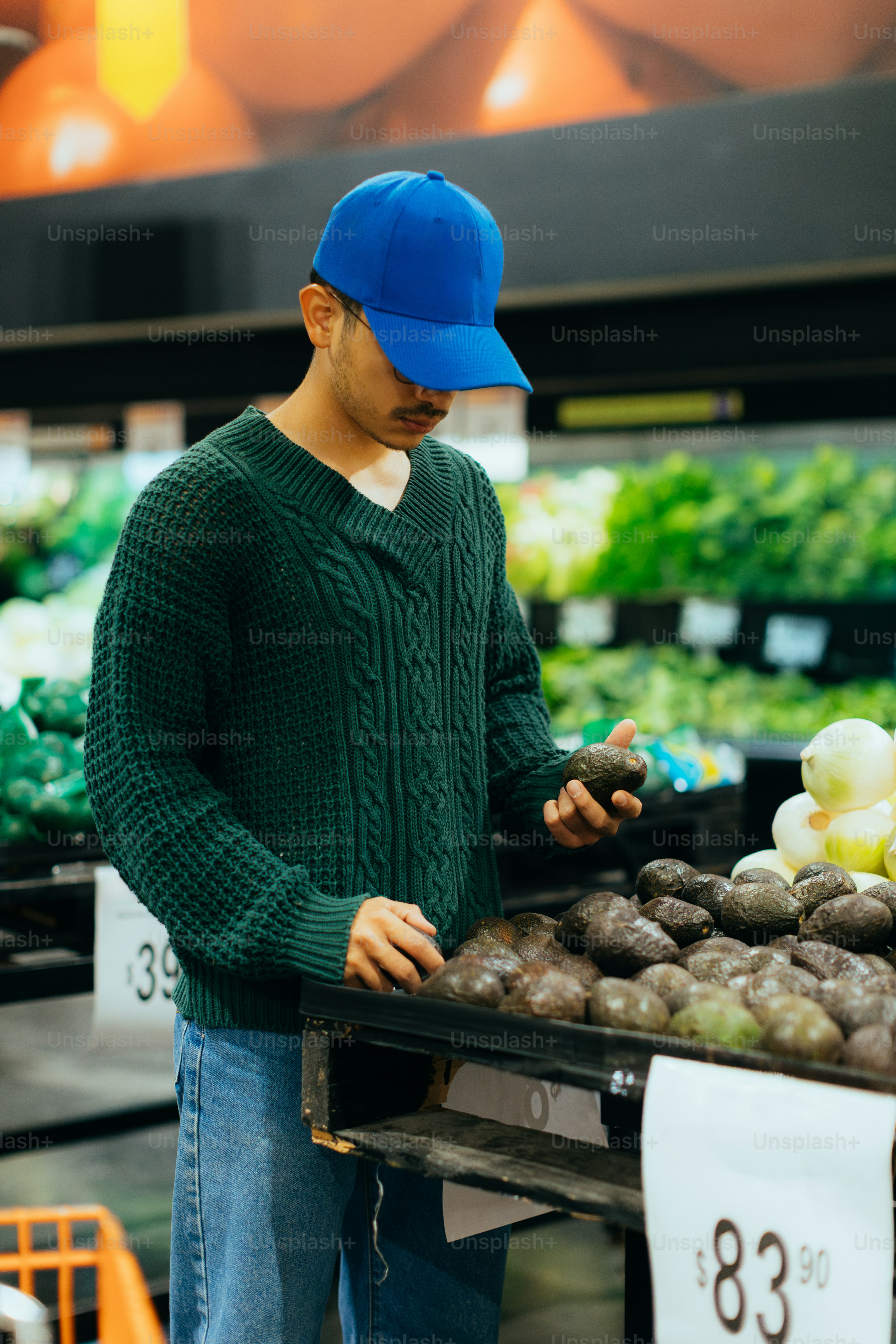 A man shops for avocados in the grocery store.