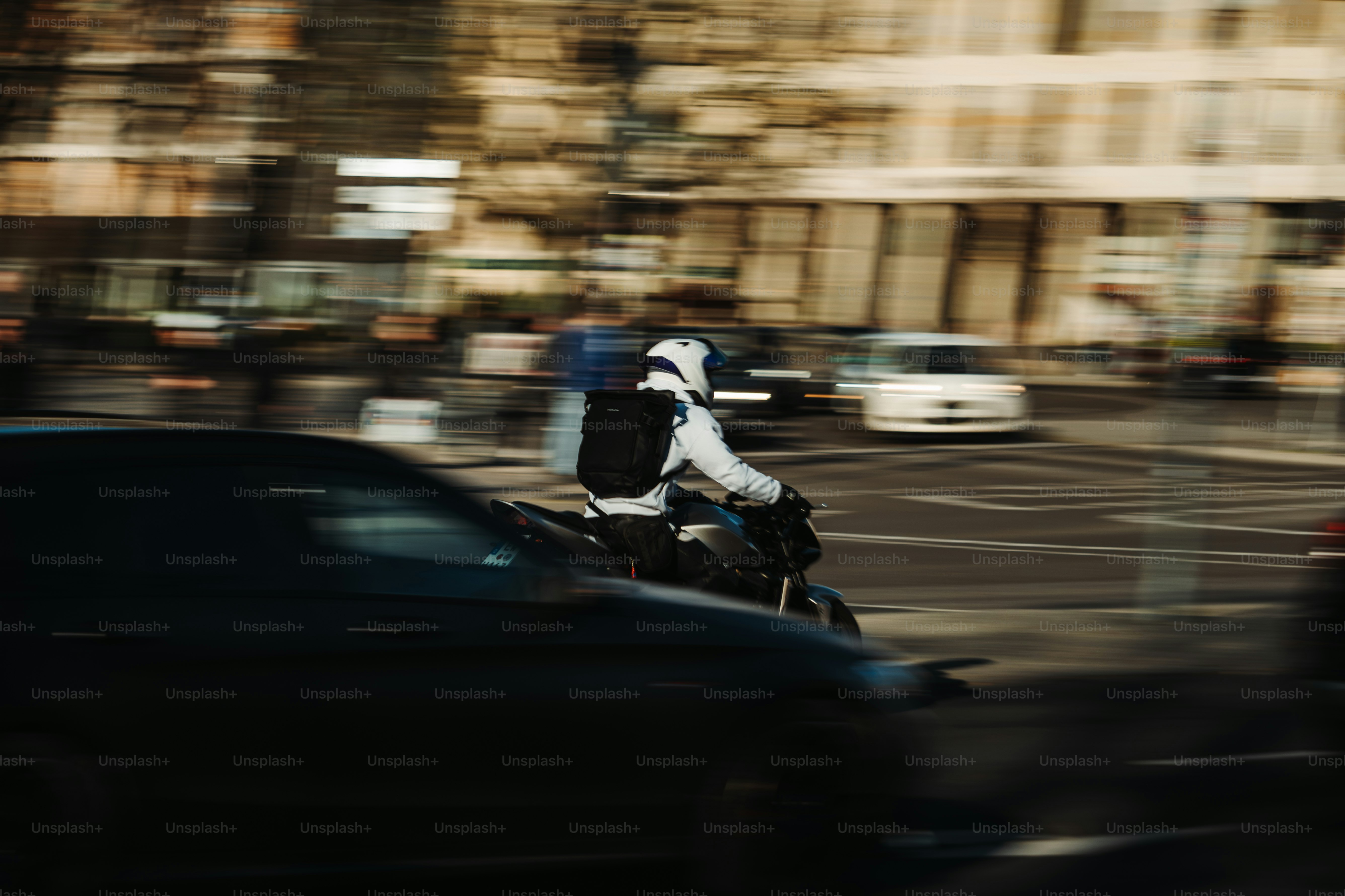 A motorcyclist speeds through city traffic.