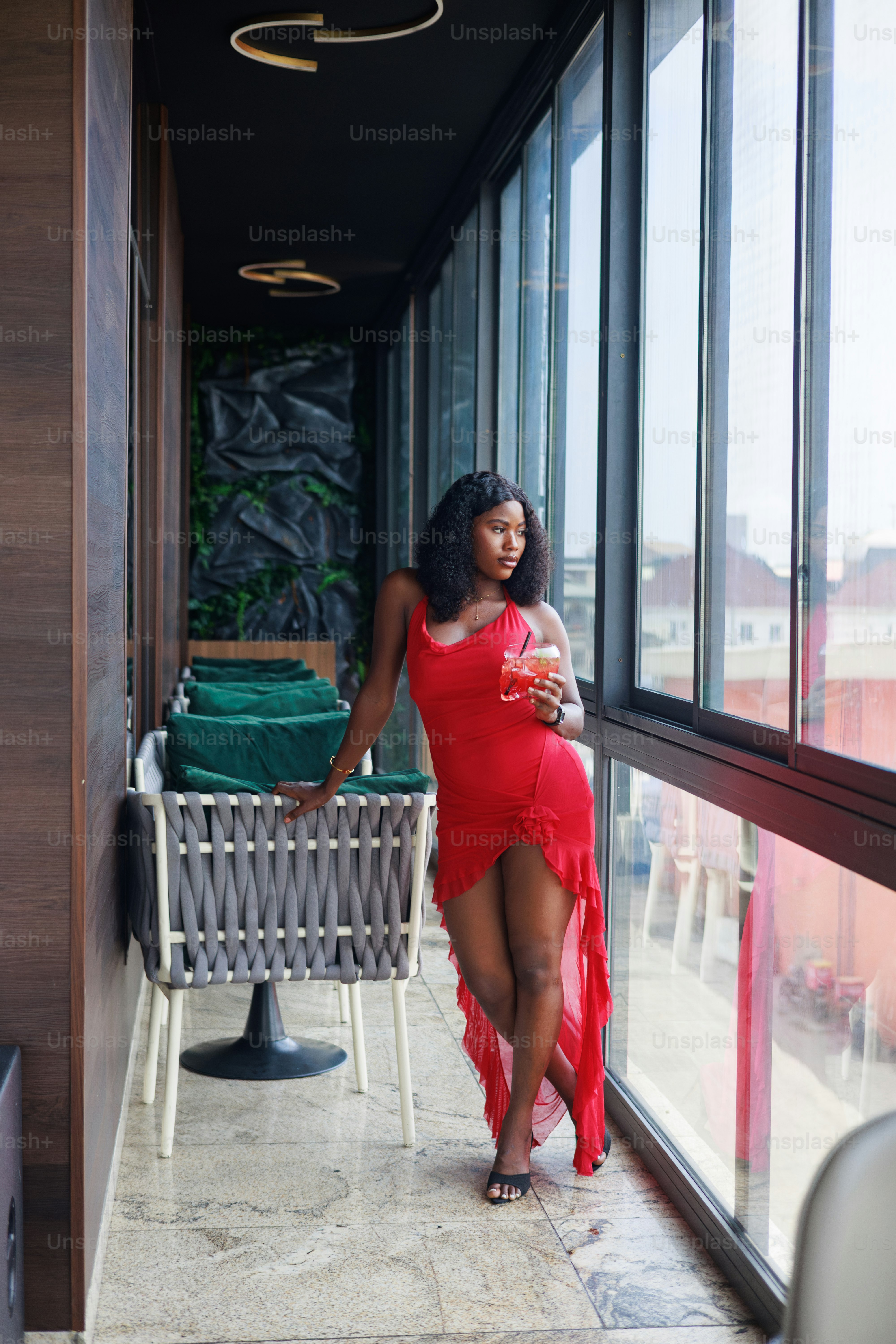A woman poses by a window with a cocktail. photo – Restaurant Image on ...